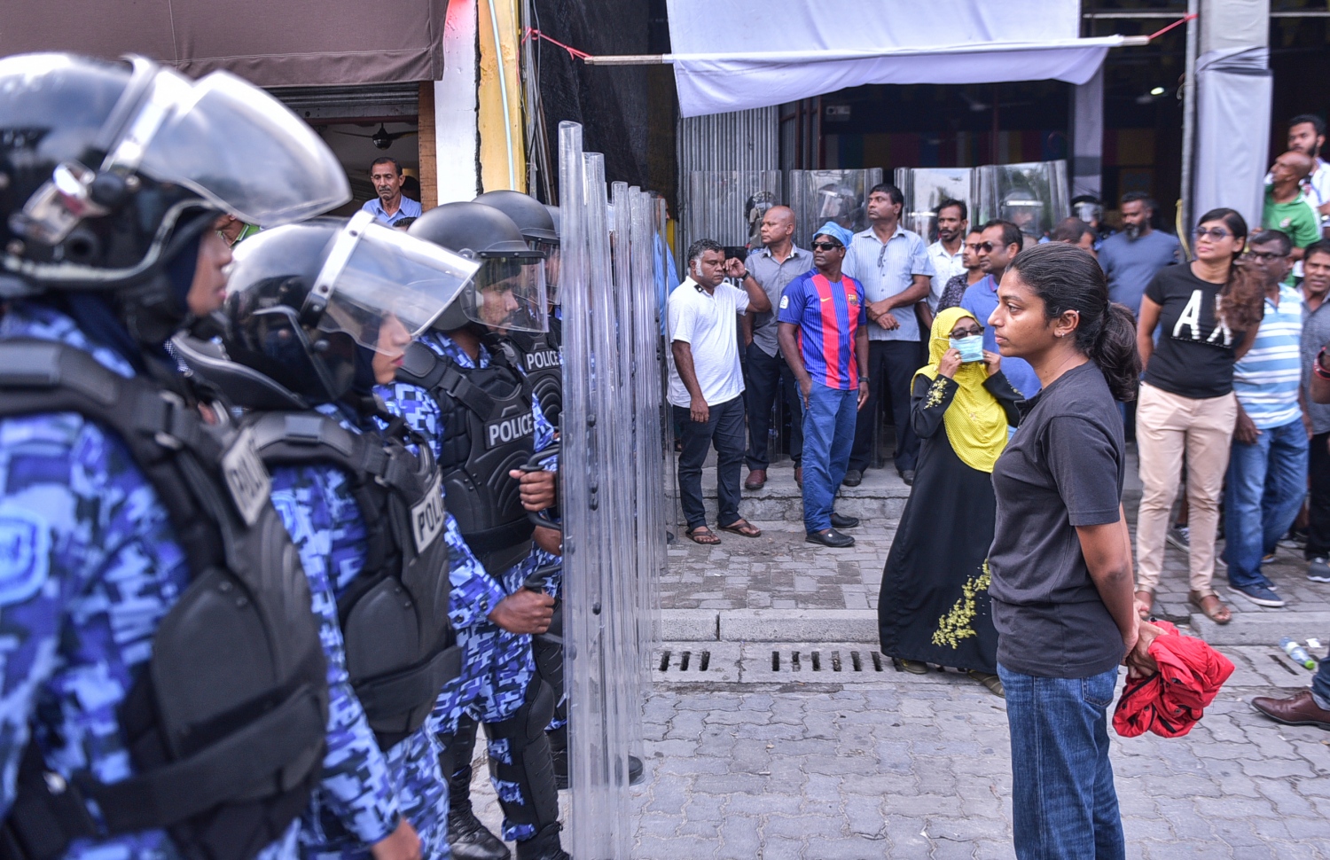 މާލެ: ފެބްރުއަރީ 16، 2018- ސަރުކާރާ ދެކޮޅަށް އިދިކޮޅު ހަރަކާތުން ފަހުގެ ތާރީޚެއްގައި ބާއްވާ ބޮޑު މުޒާހަރާ އަށް ތައްޔާރުވުމަށް "ވޯމްއަޕް މުޒާހަރާ" ގެ ނަމުގައި ކުރިއަށް ގެންދަން އުޅުނު އެއްވުން އެސްއޯ ފުލުހުން ރޫޅާލާއިރު، ގަލޮޅު އުތުރު ދާއިރާގެ އެމްޑީޕީގެ މެމްބަރު އީވާ އަބްދުﷲ، ޝީލްޑް ހިފައިގެން ތިބި ފުލުހުންގެ ކުރިމަތީގައި މަޑުކޮށްލައްވައިގެން.---ފޮޓޯ: ހުސެއިން ވަހީދު/މިހާރު