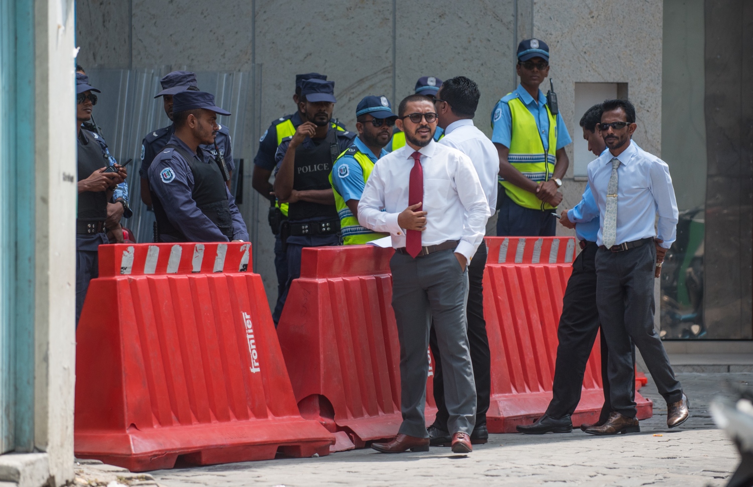 މާލެ: ފެބްރުއަރީ 19، 2018- ކުއްލި ނުރައްކަލުގެ ހާލަތުގެ ގަރާރާ މެދު ރައްޔިތުންގެ މަޖިލީހުން ގޮތެއް ނިންމުމަށް ބާއްވާ ޚާއްސަ ޖަލްސާ އަށް ދައުވަތު ލިބިވަޑައިނުގެންނެވި 12 މެމްބަރުންގެ ތެރެއިން ބައެއް ބޭފުޅުން ބޭރުގައި މަޑުކޮށްލައިގެން ތިއްބެވިއިރު، ފުލުހުން އެ ސަރަހައްދުގެ މަގު ބަންދުކޮށްގެން.---ފޮޓޯ: ހުސެއިން ވަހީދު/މިހާރު