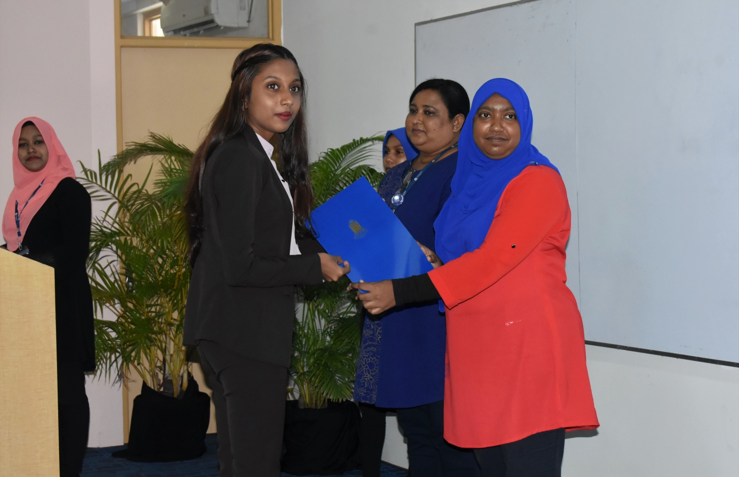 އެމްއެންޔޫގެ ސްކޮލަޝިޕް ލިބުނު ދަރިވަރަކަށް، އެ ޔުނިވާސިޓީގެ ކައުންސިލް މެމްބަރު ޑރ. ނަޒްލާ (ކ) ލިޔުން ހަވާލުކޮށްދެއްވަނީ.-- ފޮޓޯ: އެމްއެންޔޫ