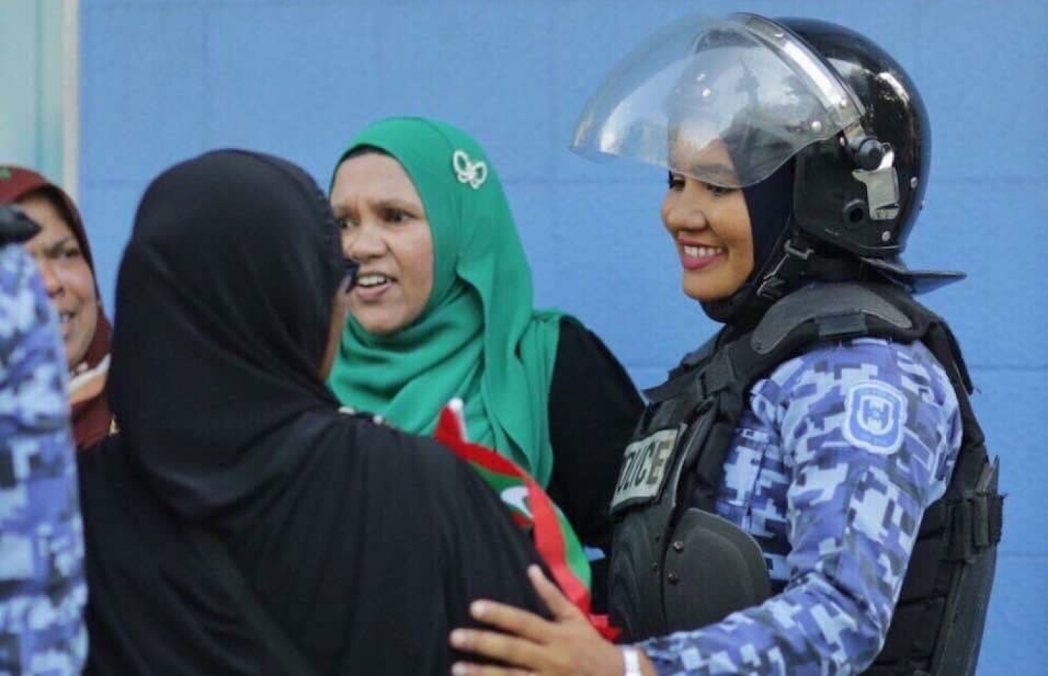 އިއްޔެގެ މުޒާހަރާގައި އަންހެން ފުލުހަކު، ހިނިތުންވުމާ އެކު އާންމުންގެ މީހަކާ މުއާމަލާތް ކުރަނީ. - ފޮޓޯ: ޝާރި