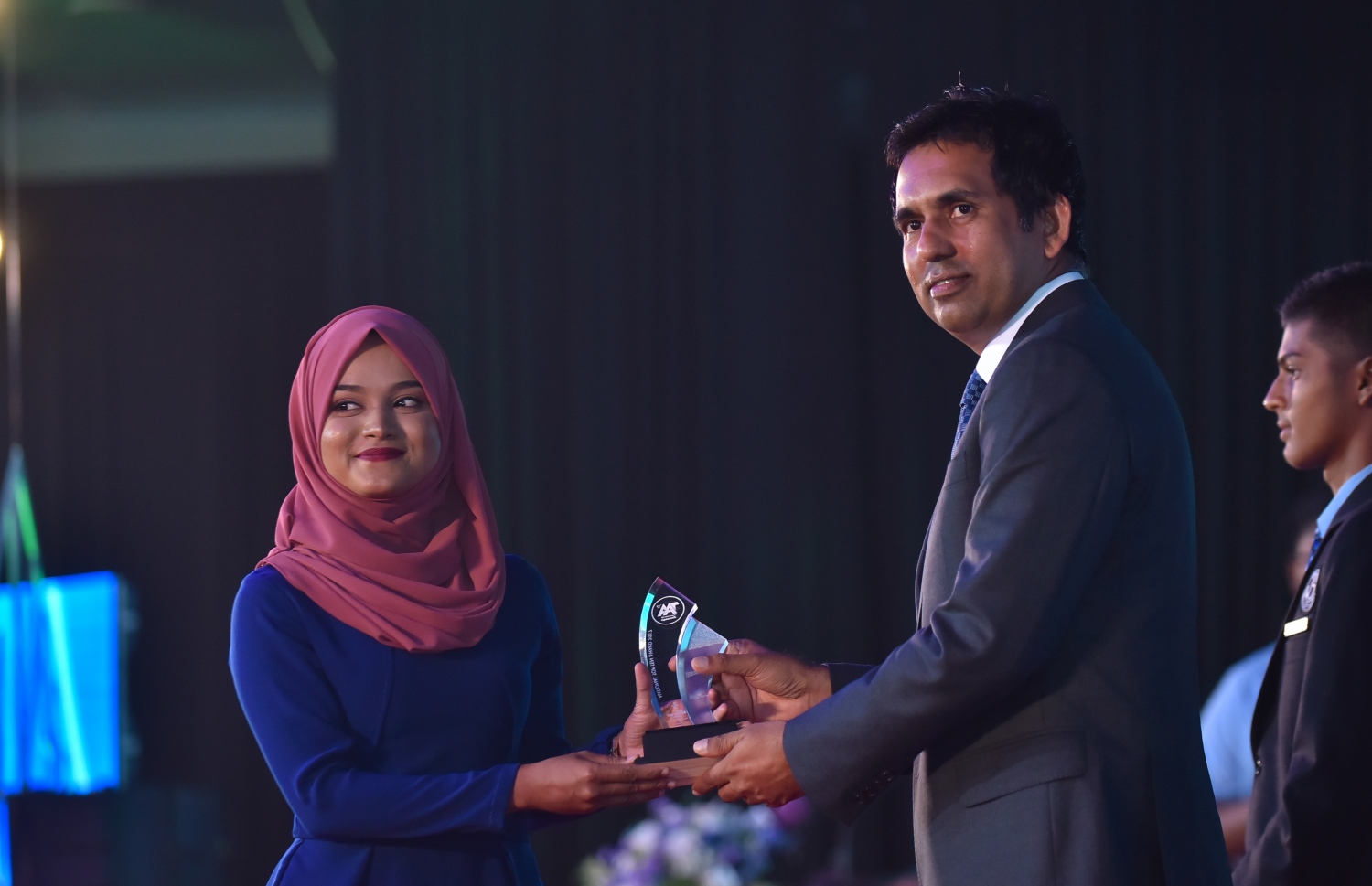 މާލެ: މާޗް 4، 2018- މިދިޔަ އަހަރުގެ އޭ ލެވެލް އިމްތިހާނުގެ ޓޮޕް އެޗީވާސް އެވޯޑް ދިނުމުގެ ރަސްމިއްޔާތުގައި، އިކޮނޮމިކް މިނިސްޓަރު މުހައްމަދު ސައީދު ދަރިވަރަކަށް އިނާމު ދެއްވަނީ---ފޮޓޯ: ހުސައިން ވަހީދު/މިހާރު