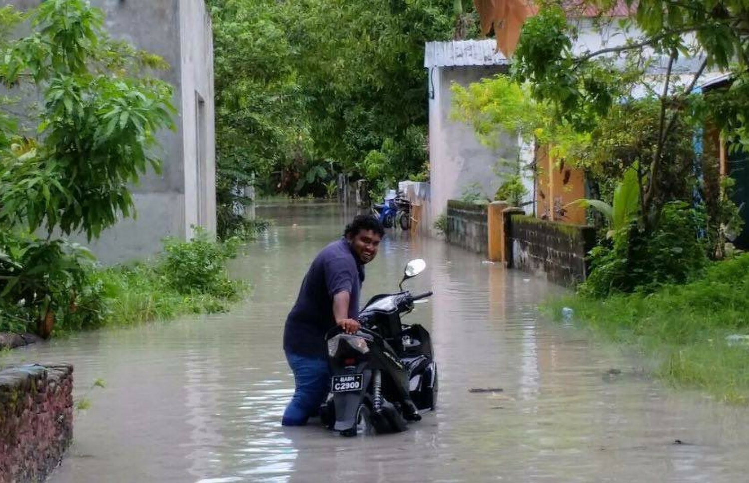 ފެންބޮޑުވެފައިވާ މަގެއްގައި މީހަކު ސައިކަލާ އެކު. ފޮޓޯ: ކިޔުންތެރިއެއް.