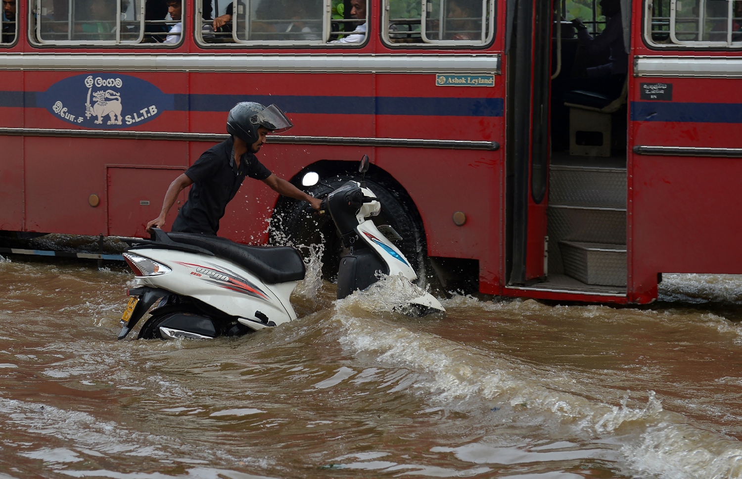 ވެރިރަށް ކޮލަމްބޯގެ ކަޑުވެލައިގައި ފެންބޮޑުވެފައިވާ ސަރަހައްދަކުން މީހަކު މޮޓޯސައިކަލް ކޮއްޕައިފައި ގެންދަނީ. --ފޮޓޯ:އޭއެފްޕީ