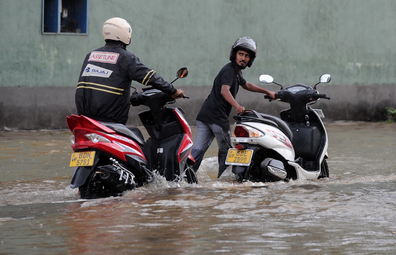 ވެރިރަށް ކޮލަމްބޯގެ ކަޑުވެލައިގައި ފެންބޮޑުވެފައިވާ ސަރަހައްދަކުން ބަޔަކު މޮޓޯސައިކަލް ކޮއްޕައިފައި ގެންދަނީ. --ފޮޓޯ:އޭއެފްޕީ