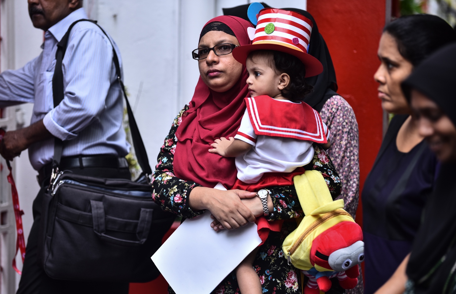 ސްކޫލުގެ ދަރިވަރަކު ބެލެނިވެރިންނާ އެކު ރިޕޯޓު ފޮތް ހިފައިގެން ދަނީ ފޮޓޯ: އަހުމަދު ނިޝާތު/ މިހާރު