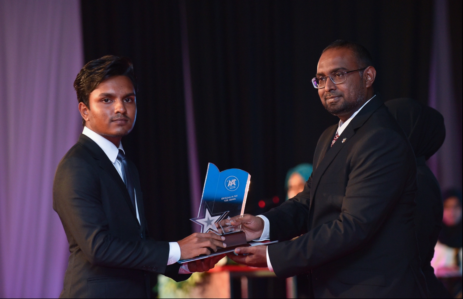 މާލެ: ޖުލައި 9، 2018: މިދިޔަ އަހަރުގެ އޮކްޓޯބަރު/ނޮވެމްބަރުގައި ބޭއްވި އޭ ލެވެލް އިމްތިހާނުން ވަނަތައް ހޯދި ދަރިވަރުންނަށް އެވޯޑު ދިނުމުގެގޮތުން ދަރުބާރުގޭގައި ބޭއްވި ރަސްމިއްޔާތުގައި، ރައީސް އޮފީހުގެ ސްޓޭޓް މިނިސްޓަރު މުޖުތާޒް، ދަރިވަރަކަށް އެވޯޑު ހަވާލުކުރައްވަނީ.--- ފޮޓޯ: ހުސައިން ވަހީދު/މިހާރު