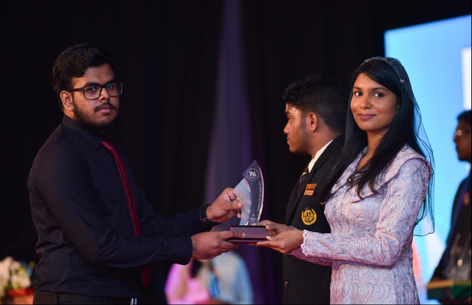 މާލެ: ޖުލައި 9، 2018: މިދިޔަ އަހަރުގެ އޮކްޓޯބަރު/ނޮވެމްބަރުގައި ބޭއްވި އޭ ލެވެލް އިމްތިހާނުން ވަނަތައް ހޯދި ދަރިވަރުންނަށް އެވޯޑު ދިނުމުގެގޮތުން ދަރުބާރުގޭގައި ބޭއްވި ރަސްމިއްޔާތުގައި، ޖެންޑާ މިނިސްޓަރު ޒެނީޝާ ޝަހީދު ޒަކީ، ދަރިވަރަކަށް އެވޯޑު ހަވާލުކުރައްވަނީ.--- ފޮޓޯ: ހުސައިން ވަހީދު/މިހާރު