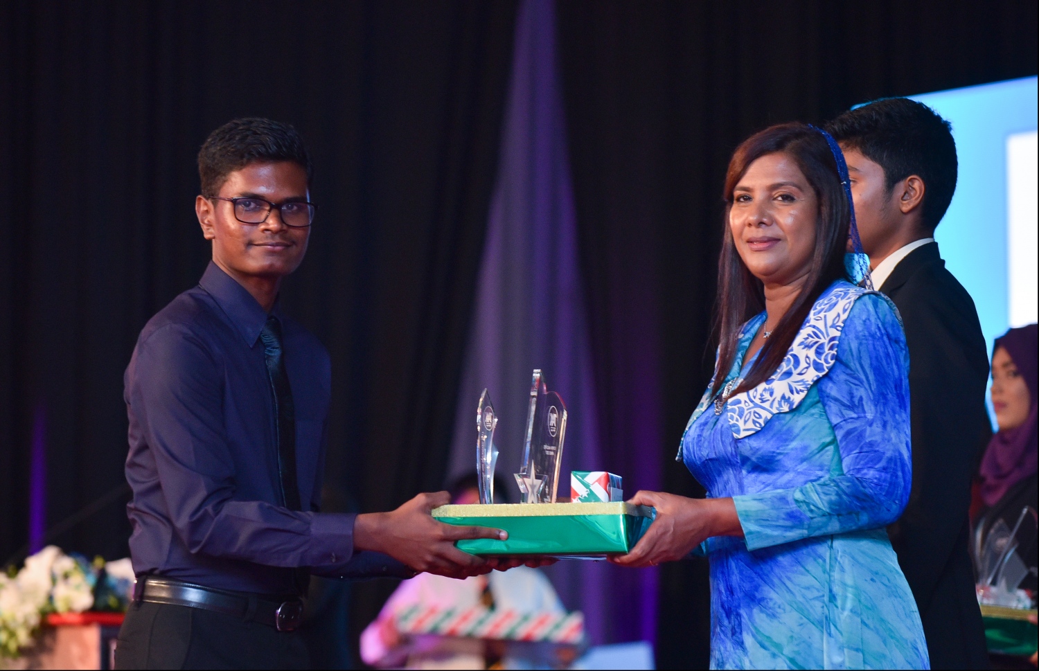 މާލެ: ޖުލައި 9، 2018- މިދިޔަ އަހަރުގެ އޮކްޓޯބަރު/ނޮވެމްބަރުގައި ބޭއްވި އޭ ލެވެލް އިމްތިހާނުގެ ރަންވަނަތައް ހޯދި ދަރިވަރުންނަށް އިނާމު ދިނުމަށް ދަރުބާރުގޭގައި ބޭއްވި ރަސްމިއްޔާތުގައި، އެޑިއުކޭޝަން މިނިސްޓަރު އާއިޝަތު ޝިހާމް، ދަރިވަރަކަށް އެވޯޑާއި އިނާމު ދެއްވަނީ.---ފޮޓޯ: ހުސެއިން ވަހީދު/މިހާރު