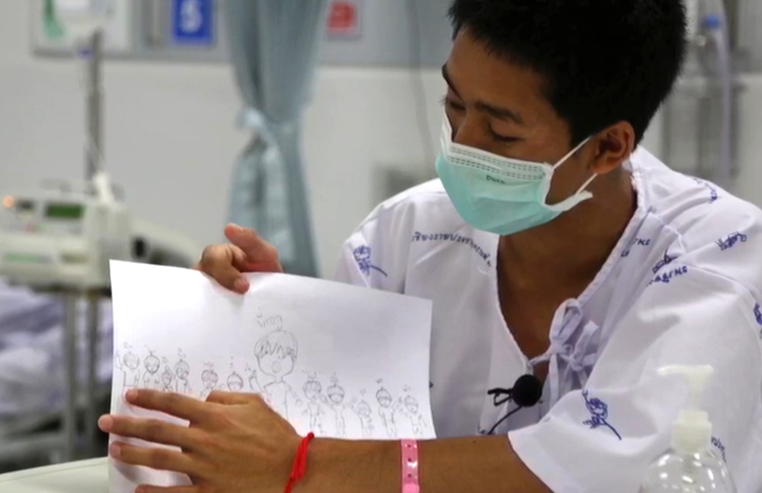 ހޮހަޅައިން ސަލާމަތް ކުރި އަދުލް ސަމޮން، 14، ކުރަހާފައިވާ އެ ކުދިންނާއި ކޯޗުގެ ކާޓޫނެއް ދައްކާލަނީ. --ފޮޓޯ: ތައިލެންޑް ހެލްތު މިނިސްޓްރީ