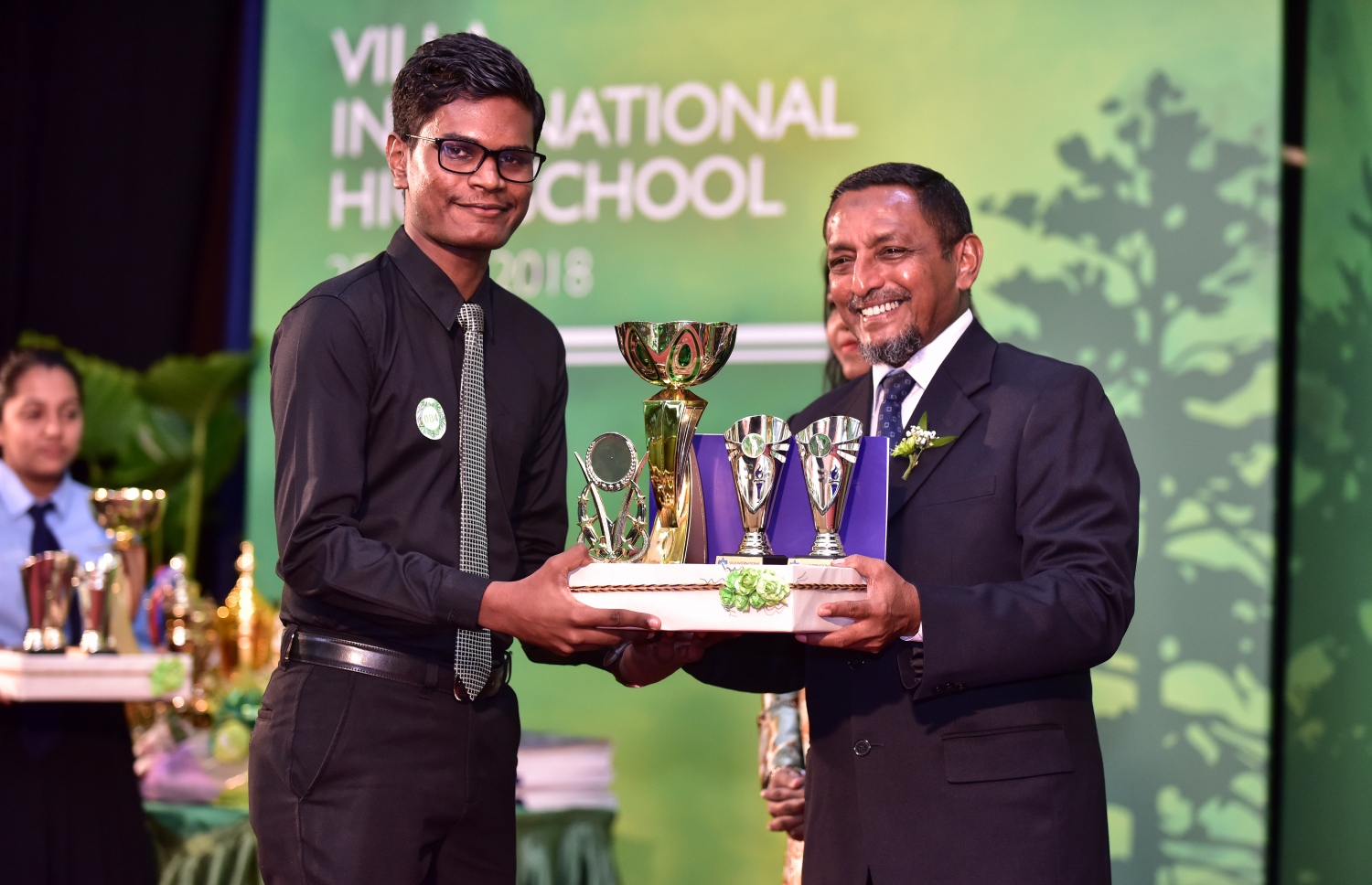 ވިލާ ހައި ސްކޫލުގެ މިދިޔަ އަހަރުގެ އިނާމު ދިނުމުގެ ޖަލްސާގައި، ވިލާ ފައުންޑޭޝަންގެ އެގްޒެކެޓިވް ޑިރެކްޓަރު މުހައްމަދު ހަމީދު،  ދަރިވަރަކަށް އެވޯޑު ހަވާލުކޮށްދެއްވަނީ-- ފޮޓޯ: ނިޝާން އަލީ/ މިހާރު