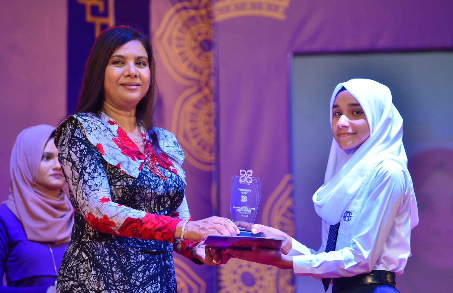 މާލެ: އޮގަސްޓް 15، 2018- ހިރިޔާ ސްކޫލުގެ މިއަހަރުގެ އިނާމު ދިނުމުގެ ޖަލްސާގައި އެސްކޫލުގެ ގަދަ 5 ގައި ހިމެނުނު ދަރިވަރަކަށް، އެޑިއުކޭޝަން މިނިސްޓަރު އައިޝަތު ޝިހާމް އިނާމު ދެއްވަނީ.---ފޮޓޯ: ހުސައިން ވަހީދު/މިހާރު