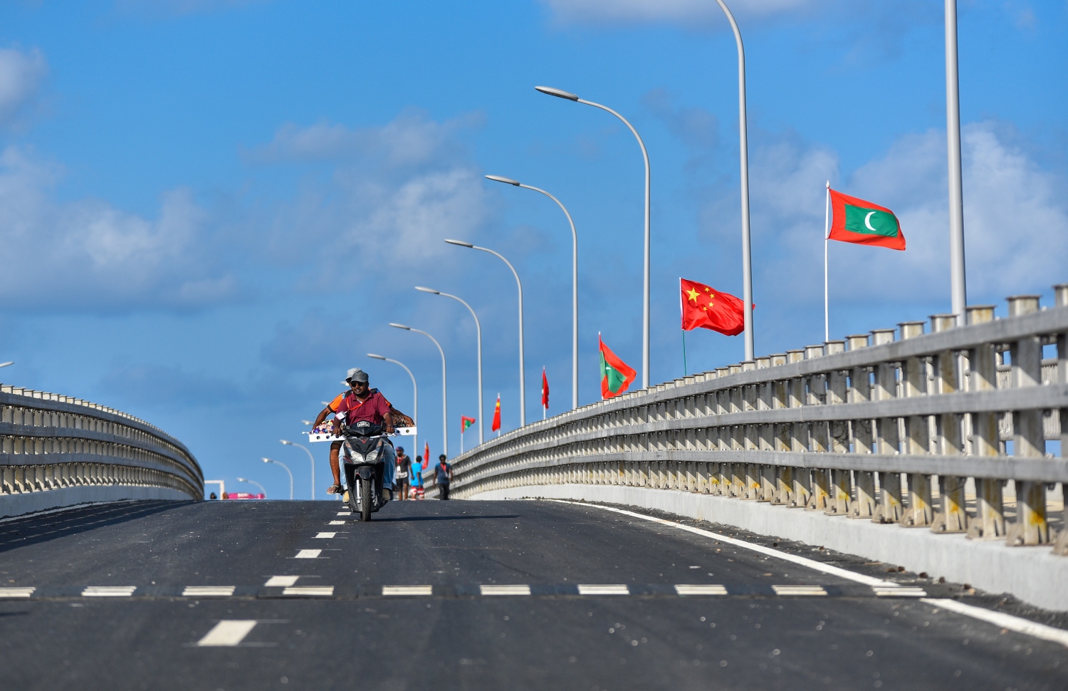 މާލެ އާއި ހުޅުލެއާ ދެމެދު އަޅާފައިވާ ސިނަމާލެ ބްރިޖުގައި ވެހިކަލްތަކަށް ހަދާފައިވާ ހަތަރު ލޭންގެ ތެރެއިން ލޭނެއްގައި، ބްރިޖުގެ ބައެއް މަސައްކަތްތަކުގައި އުޅޭ ބަޔަކު ސައިކަލެއްގައި ދުއްވާފައިދަނީ. އާންމު ދަތުރުތަކަށް ބްރިޖު ހުޅުވާލުމަށް ހަމަޖެހިފައިވަނީ އަންނަ ހުކުރު ދުވަހު.---ފޮޓޯ: ހުސައިން ވަހީދު/މިހާރު