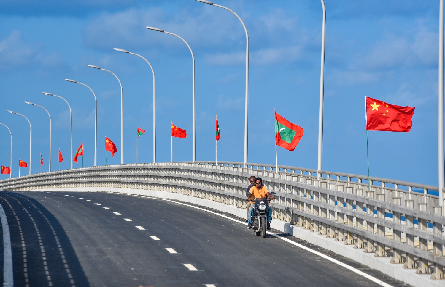 މާލެ އާއި ހުޅުލެއާ ދެމެދު އަޅާފައިވާ ސިނަމާލެ ބްރިޖުގެ ބައެއް މަސައްކަތްތަކުގައި އުޅޭ ބަޔަކު ސައިކަލެއްގައި ދުއްވާފައިދަނީ. އާންމު ދަތުރުތަކަށް ބްރިޖު ހުޅުވާލުމަށް ހަމަޖެހިފައިވަނީ އަންނަ ހުކުރު ދުވަހު.---ފޮޓޯ: ހުސައިން ވަހީދު/މިހާރު