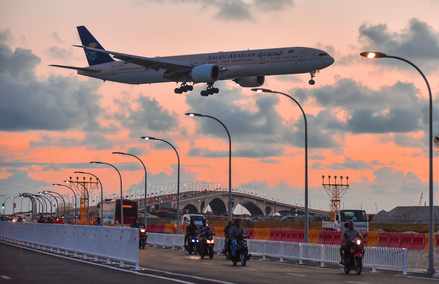 ސެޕްޓެމްބަރު 9، 2018- ސިނަމާލެ ބްރިޖު މަތިން ދުއްވާފައި ބަޔަކު ހުޅުމާލެއަށް ދާއިރު ބްރިޖް މަތިން ހުރަސްކޮށް، ސައޫދީ އެއާލައިންސްގެ މަތިންދާބޯޓެއް މިއަދުގެ އިރުއޮއްސުނު ވަގުތު، ވެލާނާ އިންޓަނޭޝަނަލް އެއާޕޯޓަށް ޖައްސަން ތައްޔާރުވެފައި: މިއީ ބްރިޖުމަތިން ވެހިކަލްތައް ދުއްވާފައި ދާއިރު ފެންނަ ހިތްގައިމު މަންޒަރެއް.---ފޮޓޯ: ހުސައިން ވަހީދު/މިހާރު