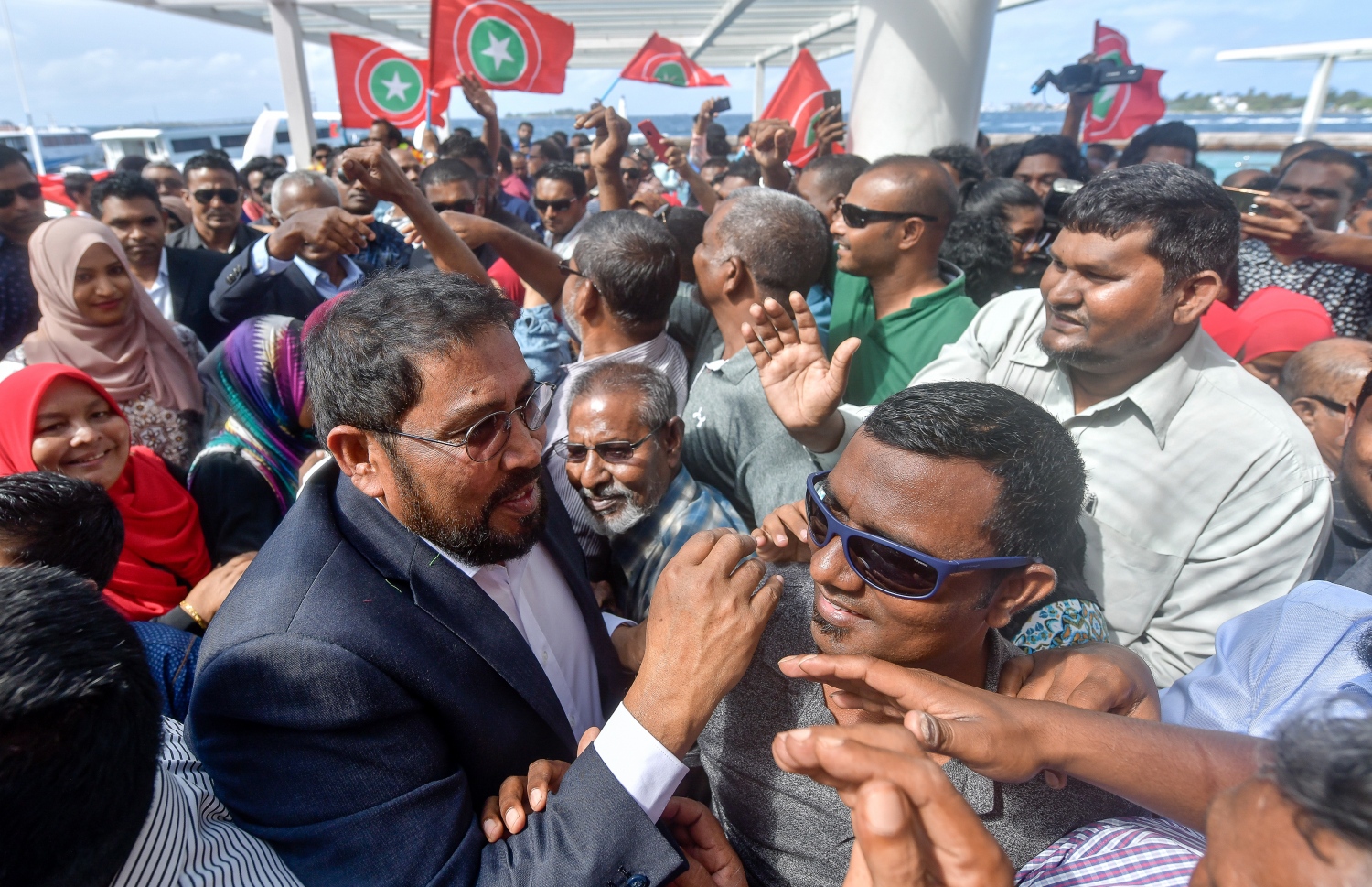 މާލެ: އޮކްޓޯބަރު 4، 2018- ޖުމްހޫރީ ޕާޓީގެ ފައުންޑަރު ގާސިމް އިބްރާހިމް، އަހަރަކަށް ވުރެ ގިނަ ދުވަހު ރާއްޖެއިން ބޭރުގައި އުޅުއްވުމަށް ފަހު، ރާއްޖެ ވަޑައިގަތުމުން، މާލޭގެ ރަސްމީ ފާލަމުން އޭނާއަށް މަރުހަބާ ދަންނަވަން އެއްވި މީހުންނާ ސަލާމް ކުރައްވަނީ.---ފޮޓޯ: ނިޝާން އަލީ/މިހާރު