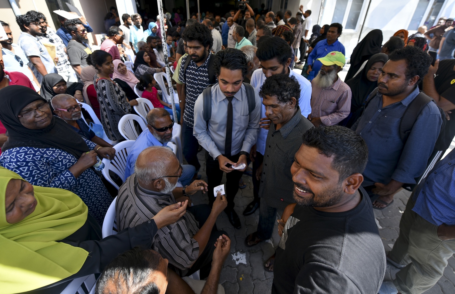 މާލެ: އޮކްޓޯބަރު 10، 2018: ހުޅުމާލޭގެ ދެ ވަނަ ފިޔަވަހިން 400 ގޯތި ގަންނަން ބޭނުންވާ މީހުންނަށް އެ ފުރުސަތު ހުޅުވާލުމާ އެކު، ގޯތީގެ ފޯމު ލުމަށް ހައުސިން މިނިސްޓްރީ ކައިރީގައި ކިޔޫ ހަދައިގެން ތިބި މީހުންނަށް ކިޔޫ ނަމްބަރު ހަވާލުކުރަނީ---ފޮޓޯ: އަހުމަދު ނިޝާތު/މިހާރު