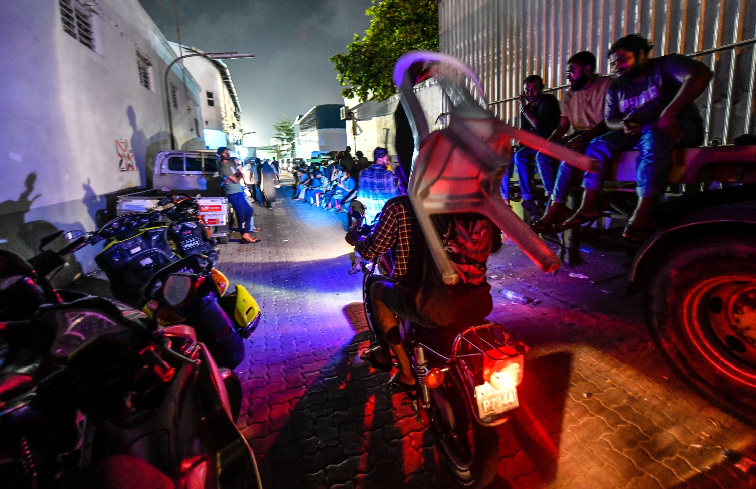 މާލެ: އޮކްޓޯބަރު 10، 2018: ހުޅުމާލޭގެ ދެ ވަނަ ފިޔަވަހިން 400 ގޯތި ގަންނަން ބޭނުންވާ މީހުންނަށް އެ ފުރުސަތު ހުޅުވާލުމާ އެކު، ހައުސިން މިނިސްޓްރީ ކައިރީގައި ދަމާލި ކިޔޫ ދިގުދެމިގެން އައިސް މިއަދު ދޫކުރި 500 ނަމްބަރު ހުސްވުމުން، މާދަމާ ދޫކުރާ 500 ނަމްބަރުގައި ލައްވާލާތޯ މިރޭގެ ނިދި ނަގާލުމަށްފަހު ގިނައަދަދެއްގެ މީހުން ހައުސިން މިނިސްޓްރީ ހުންނަ އިމާރާތާ ޖެހިގެން ހުންނަ އެސްޓީއޯ ގުދަންތައް ކައިރި މާދަމާގެ ކިޔޫގައި މަޑުކޮށްގެންތިބި އިރު ކިޔޫގައި ބައިވެރިވުމަށް މީހަކު ގޮނޑިއެއް ކޮނޑައްލައިގެން ސައިކަލުގައި ދަނީ،---ފޮޓޯ: ހުސައިން ވަހީދު/މިހާރު