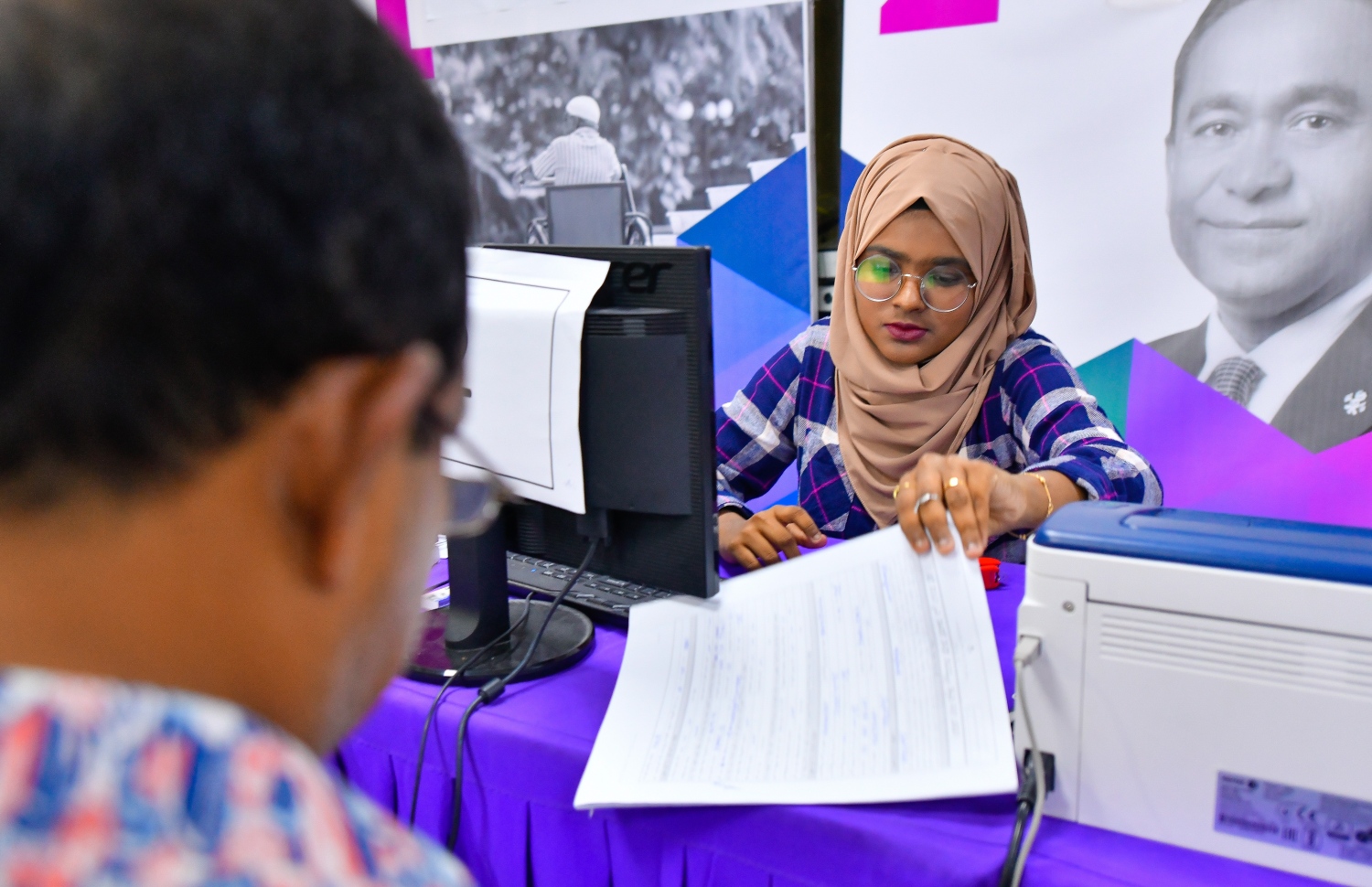 މާލެ: އޮކްޓޯބަރު 10، 2018: ހުޅުމާލޭގެ ދެ ވަނަ ފިޔަވަހިން 400 ގޯތި ގަންނަން ބޭނުންވާ މީހުންނަށް އެ ފުރުސަތު ހުޅުވާލުމާ އެކު، ހައުސިން މިނިސްޓްރީ ކައިރީގައި ދަމާލި ދިގު ކިޔޫގައި ބައިވެރިވެގެން މިއަދު ދޫކުރި 500 ނަމްބަރު ނެގި މީހުންގެ ތެރެއިން މީހެއްގެ ފޯމު މިނިސްޓްރީގެ މުވައްޒަފަކު ބަލައިގަންނަނީ،---ފޮޓޯ: ހުސައިން ވަހީދު/މިހާރު