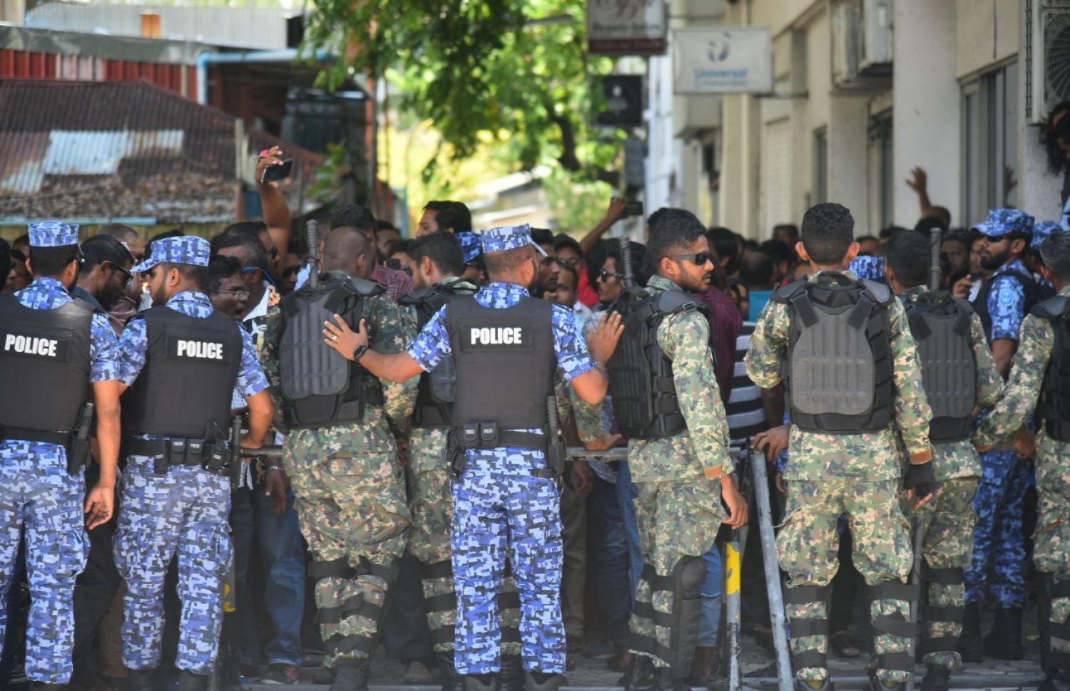 މާލެ: އޮކްޓޯބަރު 14، 2018: ސުޕްރީމް ކޯޓުގެ ހުޅަނގު ކަންމަތިން ކުރިމަތީގައި ހުންނަ ޔުނިވާސަލްގެ އިމާރާތުގެ ގޯޅިގަނޑަށް އެއްވެފައި ތިބި މީހުން ފަހަތަށް ޖެއްސުމަށް އެސްއޯ ފުލުހުންނާއި ސިފައިން ހަރަކާތްތެރިވަނީ.---ފޮޓޯ: އަހުމަދު ނިޝާތު/މިހާރު