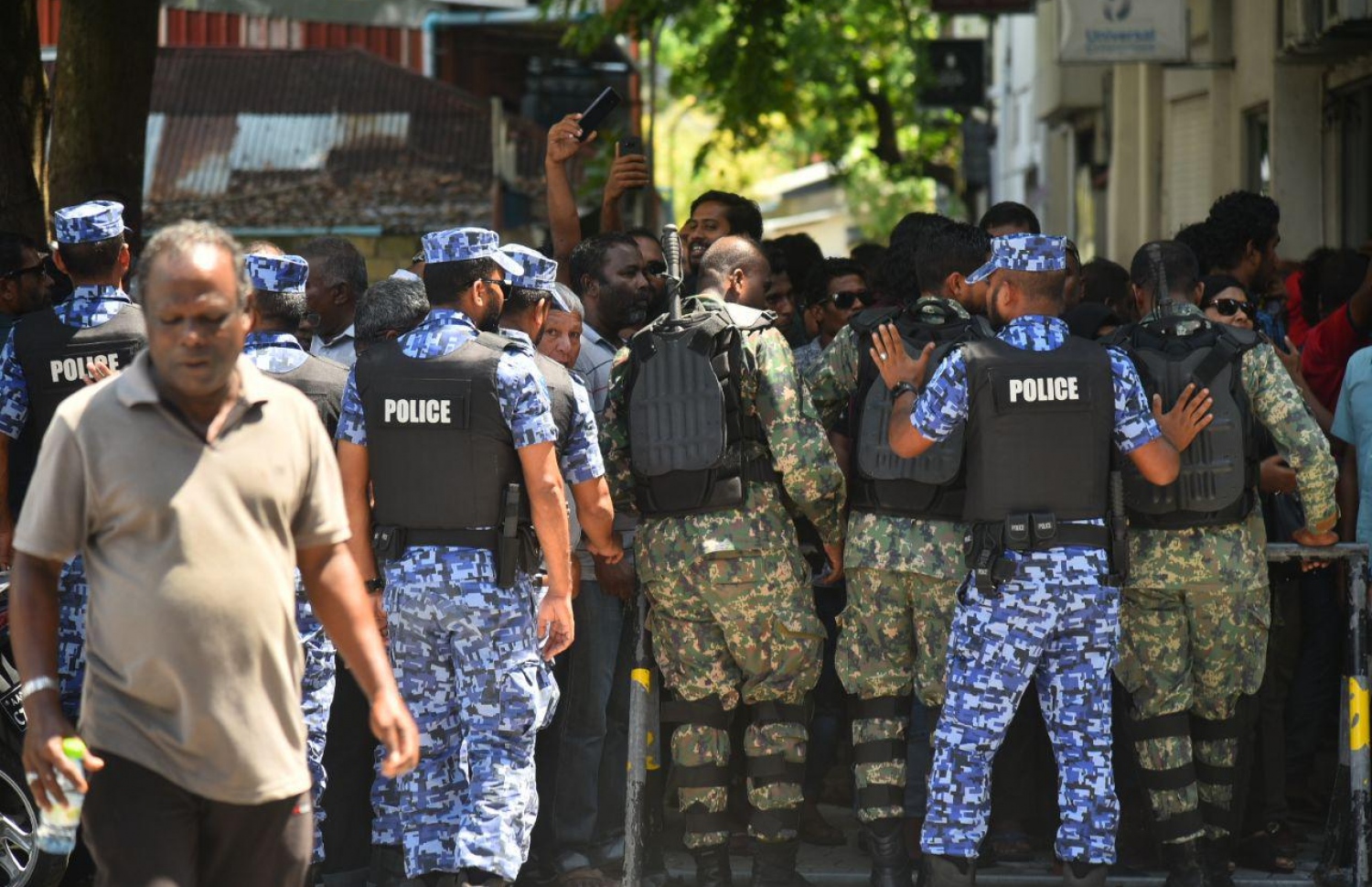 މާލެ: އޮކްޓޯބަރު 14، 2018: ސުޕްރީމް ކޯޓުގެ ހުޅަނގު ކަންމަތިން ކުރިމަތީގައި ހުންނަ ޔުނިވާސަލްގެ އިމާރާތުގެ ގޯޅިގަނޑަށް އެއްވެފައި ތިބި މީހުން ފަހަތަށް ޖެއްސުމަށް އެސްއޯ ފުލުހުން ހަރަކާތްތެރިވަނީ.---ފޮޓޯ: އަހުމަދު ނިޝާތު/މިހާރު