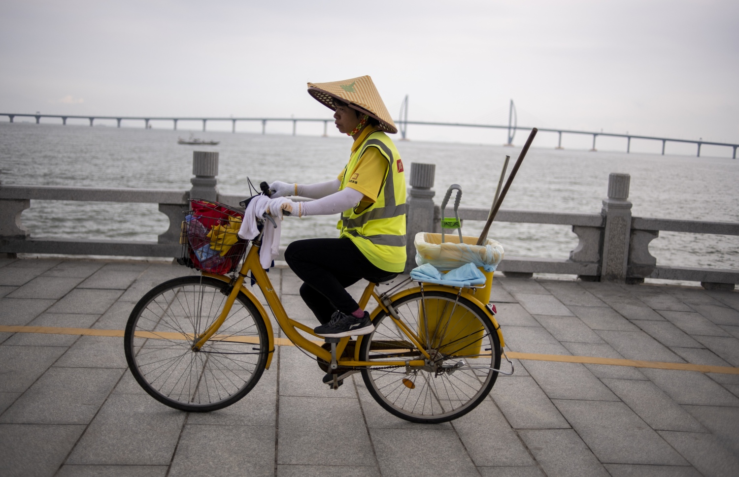 ހޮންކޮން-ޒުހައި-މަކާއޫ ބްރިޖުގެ ކައިރިން ޗައިނާގެ މަސައްކަތު މީހަކު ބައިސްކަލްގައި ދަނީ. --ފޮޓޯ:އޭއެފްޕީ