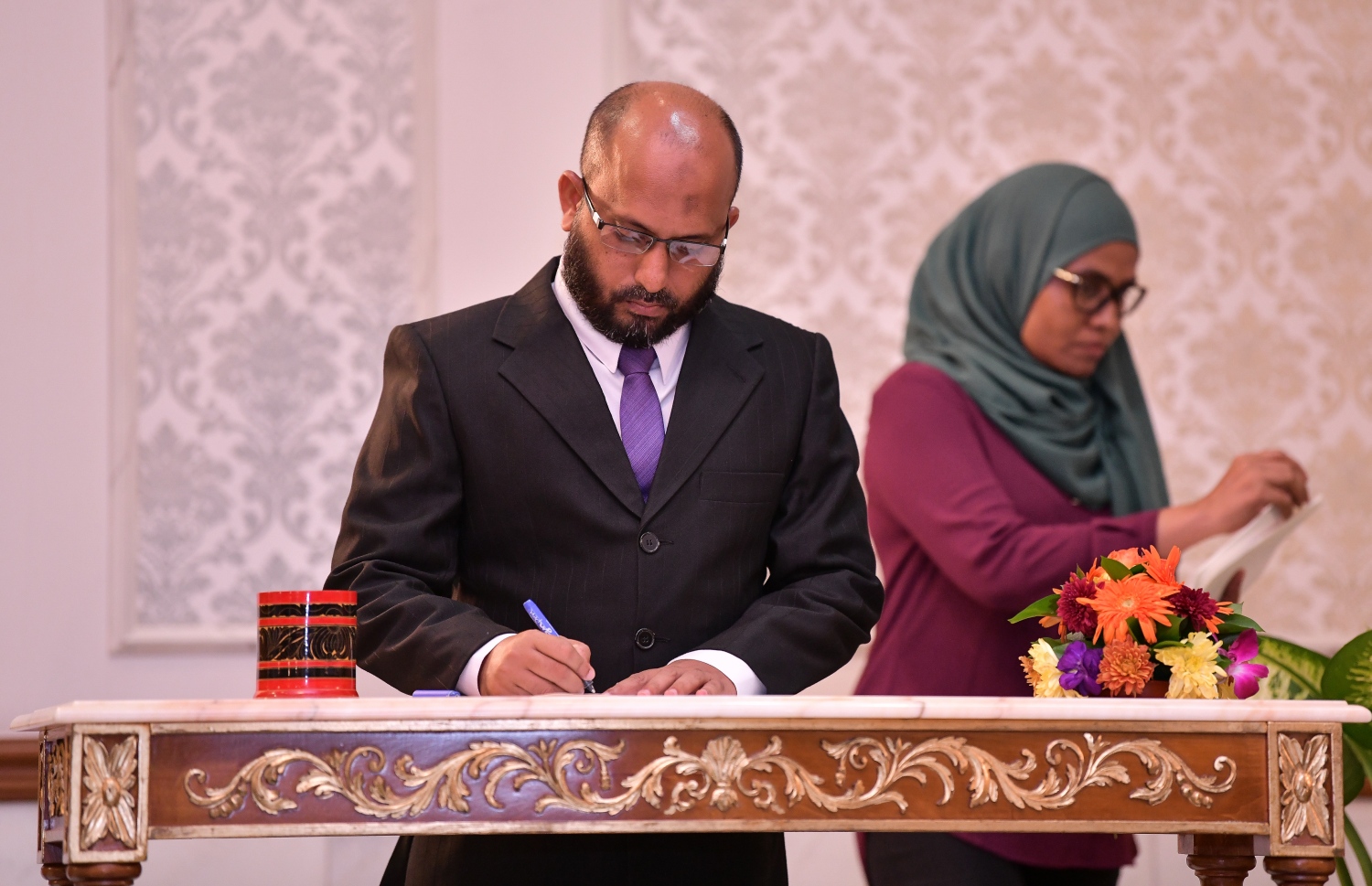 މާލެ: އޮކްޓޯބަރު 29، 2018: ރަށްރަށުގެ މެޖިސްޓްރޭޓް ކޯޓުތަކަށް 15 މެޖިސްޓްރޭޓަކު އައްޔަން ކުރައްވައި އެ ބޭފުޅުން މަގާމުގެ ހުވާ ކުރައްވުމަށް ރޭ ސުޕްރީމް ކޯޓްގައި ބޭއްވި ރަސްމިއްޔާތުގައި މެޖިސްޓްރޭޓް ކަމަށް އައްޔަން ކުރި ބޭފުޅަކު މެޖިސްޓްރޭޓް ކަމުގެ ހުވާ ކުރެއްވުމަށްފަހު ފަތްކޮޅުގައި ސޮއި ކުރައްވަނީ--. ފޮޓޯ: ނިޝާން އަލީ/މިހާރު
