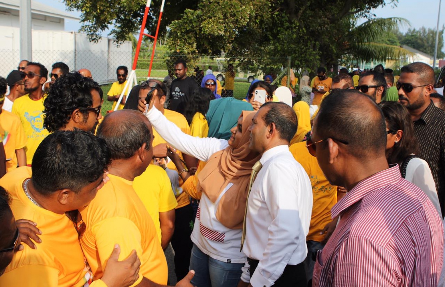 އައްޑޫ :ނޮވެމްބަރު 5، 2018: ކުރީގެ ރައީސް މުހައްމަދު ނަޝީދު އައްޑޫއަށް ކުރެއްވި ދަތުރުފުޅުގައި ނަޝީދަށް މަރުހަބާ ކިއުމަށް އެއްވެ ތިބި ބައެއް މީހުންގެ ތެރެއިން އަންހެން ކުށްޖަކާއެކު ސެލްފީއެއް ނަގަން ހުއްޓިލައިގެން .-- ފޮޓޯ: އެމްޑީޕީ