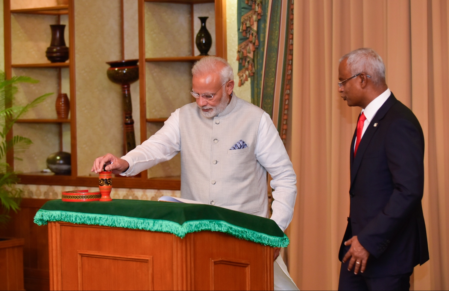 އިންޑިއާގެ ބޮޑުވަޒީރު ނަރެންދުރަ މޯދީ އިއްޒަތްތެރިން ސޮއި ކުރައްވާ ފޮތުގައި ސޮއި ކުރައްވާއިރު، އެމަނިކުފާނުގެ އަރިހުގައި ރައީސް އިބްރާހިމް މުހައްމަދު ސޯލިހް. --- ފޮޓޯ: ރައީސް އޮފީސް