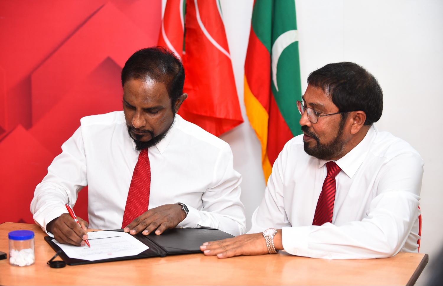 މާލެ: ނޮވެމްބަރު 25، 2018- ކަނޑިތީމު ދާއިރާގެ ޕީޕީއެމްގެ މެމްބަރު މުހައްމަދު ހުސައިން ޖުމްހޫރީ ޕާޓީއަށް ސޮއިކުރައްވާއިރު، އެ ޕާޓީގެ ލީޑަރު ގާސިމް އެ ރަސްމިއްޔާތުގައި ބައިވެރިވެވަޑައިގަންނަވަނީ.---ފޮޓޯ: ހުސައިން ވަހީދު/މިހާރު