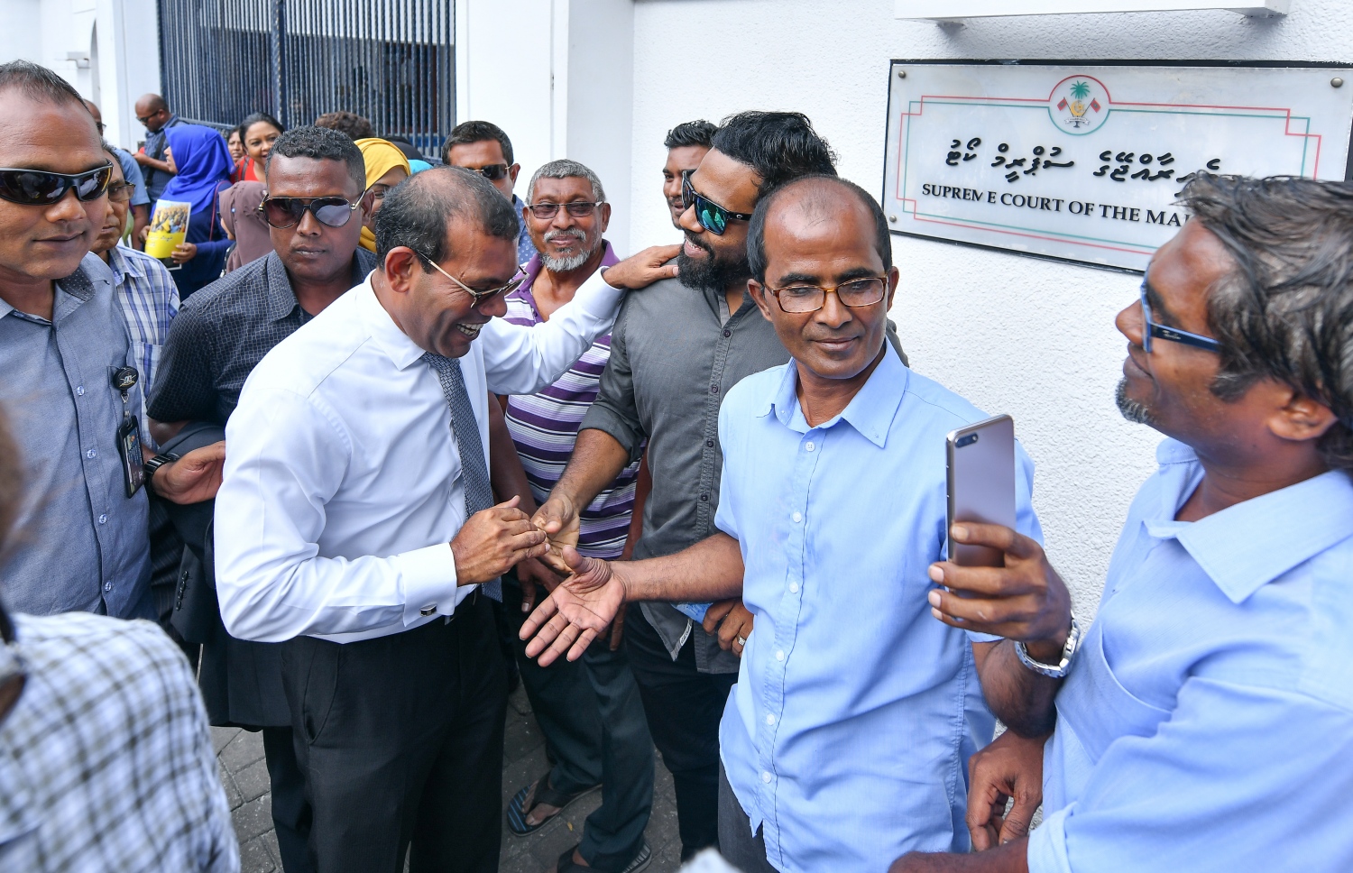 މާލެ: ނޮވެމްބަރު 26، 2018: ސުޕްރީމް ކޯޓުގައި އޮތް، ކުރީގެ ރައީސް މުހައްމަދު ނަޝީދުގެ އަޑުއެހުމަށް ފަހު، އެމަނިކުފާނު ކޯޓުން ނިކުމެ ވަޑައިގަން ސަޕޯޓަރުންނާ ސަލާމް ކުރައްވަނީ: ކޯޓުން ވަނީ އެމަނިކުފާނުގެ މައްޗަށް އިއްވި 13 އަހަރުގެ ޖަލު ހުކުމް ބާތިލް ކޮށްފައި.-- ފޮޓޯ: ނިޝާން އަލީ /މިހާރު