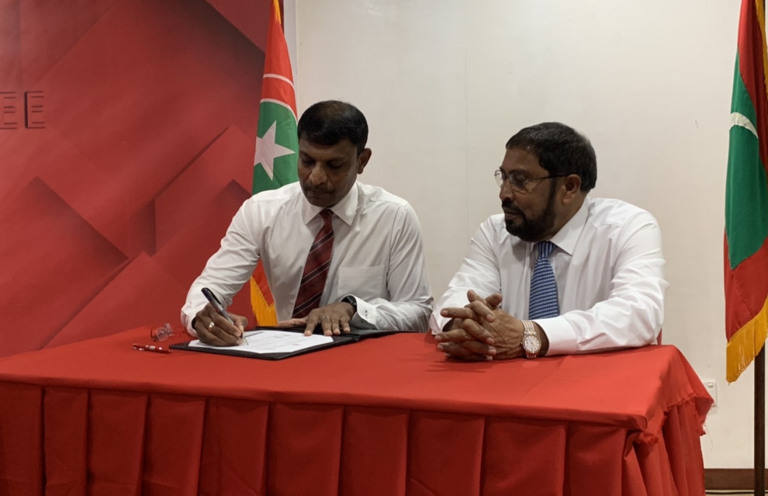 ރިޔާޒް މިރޭ ޖޭޕީއަށް ސޮއިކުރައްވާއިރު އޭނާގެ އަރިހުގައި އެ ޕާޓީގެ ލީޑަރު ގާސިމް.---ފޮޓޯ: ޖޭޕީ