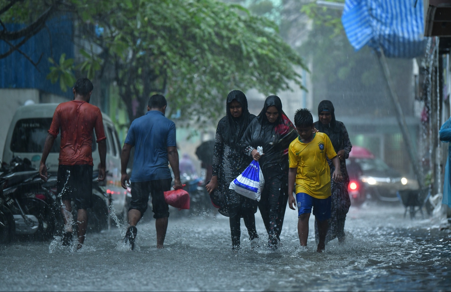 މާލެ: ޑިސެމްބަރު 5، 2018: މާލޭގައި ފެން ބޮޑުވެފައިވާ މަގަކުން ބަޔަކު ފެންގަނޑު ތެރޭގައި ހިނގާފައި ދަނީ.---ފޮޓޯ: ހުސައިން ވަހީދު/މިހާރު