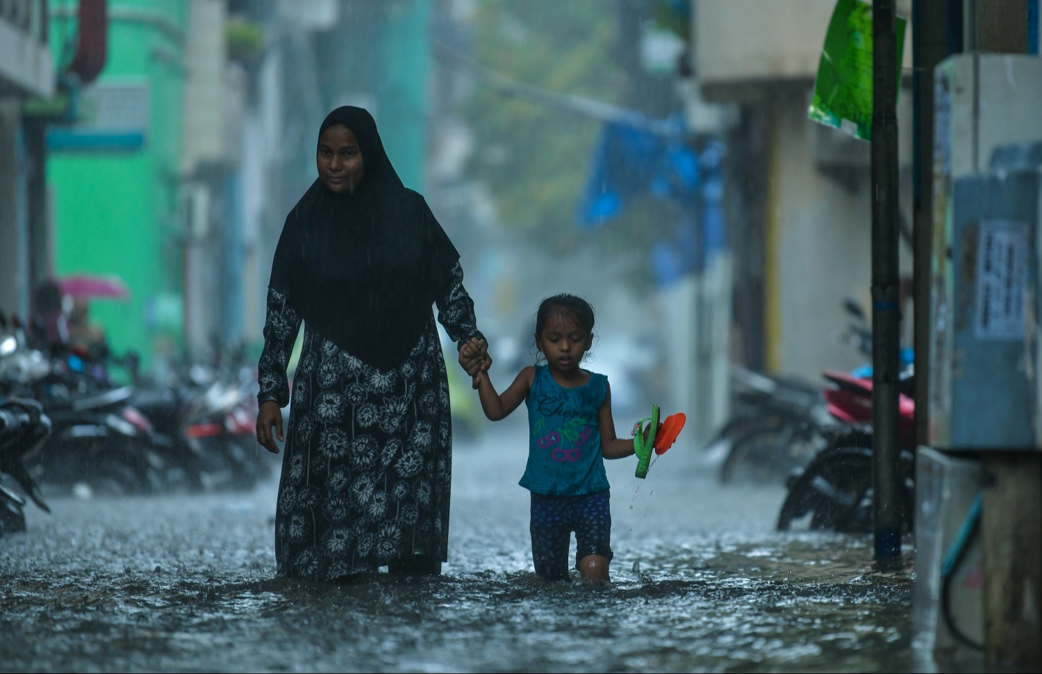 މާލެ: ޑިސެމްބަރު 5، 2018: މާލޭގައި ފެން ބޮޑުވެފައިވާ މަގަކުން އަންހެނަކު ކުޑަކުއްޖަކު ގޮވައިގެން ފެންގަނޑު ތެރޭގަިއ ހިނގާފައި ދަނީ.---ފޮޓޯ: ހުސައިން ވަހީދު/މިހާރު