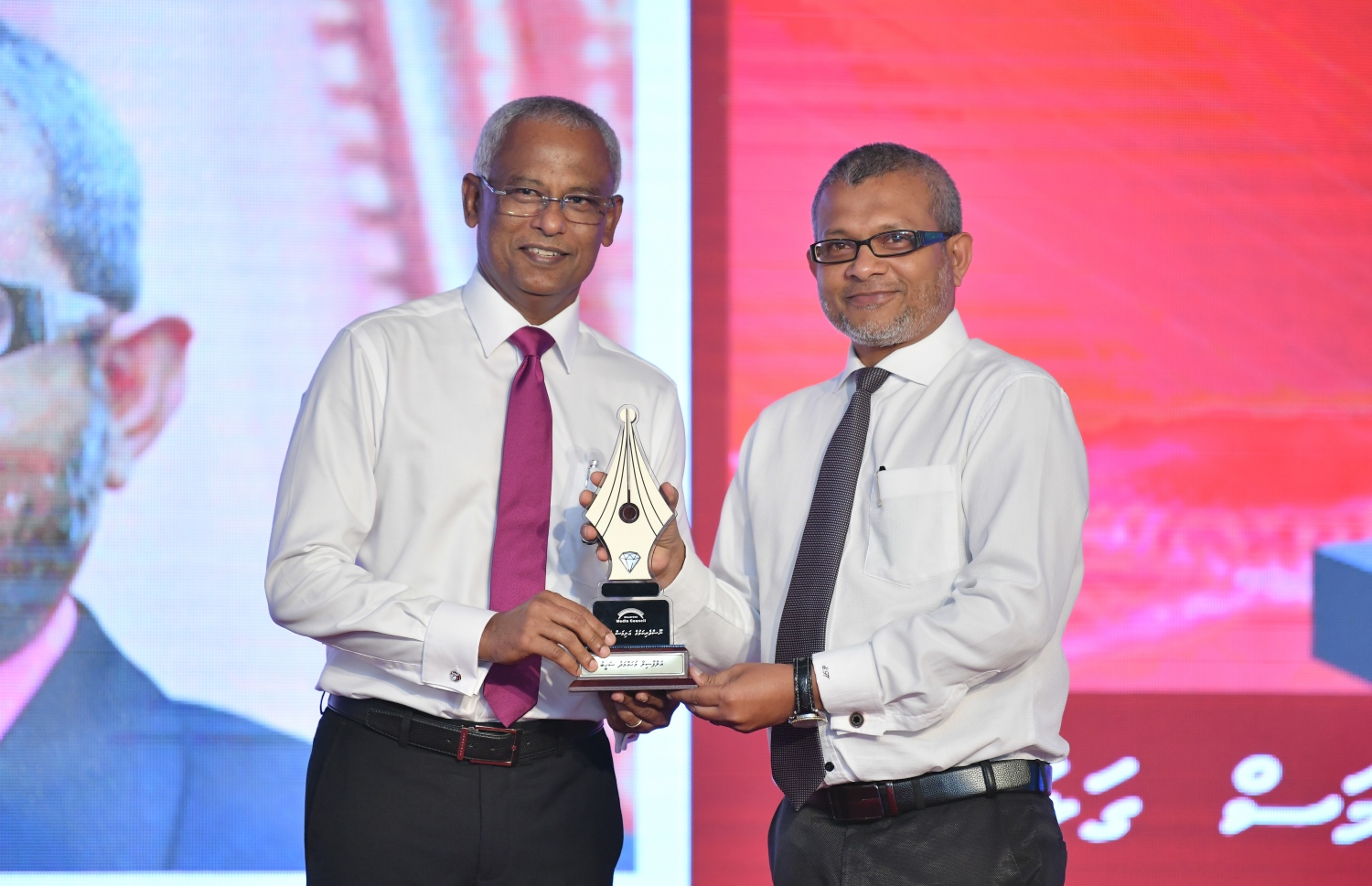 މާލެ: ޑިސެމްބަރު 11، 2018: ރާއްޖޭގެ ނޫސްވެރިކަމަށް 75 އަހަރު ފުރުމުގެ އަލިމަސްޔޫބީލް ފާހަގަ ކުރުމަށާއި ނޫސްވެރިކަމުގެ މިދިޔަ އަހަރުގެ އިނާމުތައް ދިނުމަށް މޯލްޑިވްސް މީޑިއާ ކައުންސިލާއި ހޯމް މިނިސްޓްރީ ގުޅިގެން ބޭއްވި ޖަލްސާގައި ނޫސްވެރިކަމުގެ ރަން ގަލަން ހާސިލްކުރެއްވި ބްރޯޑްކޮމްގެ ރައީސް މުހައްމަދު ޝަހީބުއަށް ރައީސް އިބްރާހިމް މުހައްމަދު ސޯލިހް އެވޯޑު ދެއްވަނީ.---ފޮޓޯ: އަހުމަދު ނިޝާތު/މިހާރު