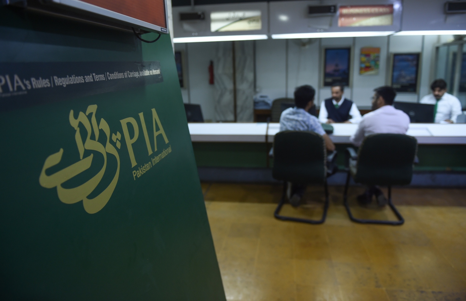 ކަރާޗީގައި ޕާކިސްތާން އިންޓަނޭޝަނަލް އެއާލައިންސް (ޕީއައިއޭ)ގެ އޮފީހުގައި ސްޓާފުން ޕަސިންޖަރުންނާ ވާހަކަ ދައްކަނީ. --ފޮޓޯ:އޭއެފްޕީ