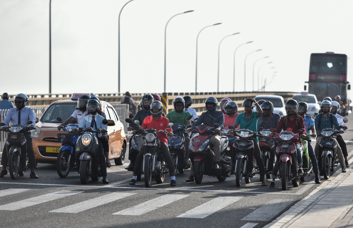 ލެ: މާޗް 10، 2019- ބްރިޖާއި ހައިވޭން ދަތުރު ކުރާއިރު ހެލްމެޓް އެޅުން މަޖުބޫރު ކުރުމުން މިއަދު ހެނދުނު ހެލްމެޓް އަޅައިގެން ތިބި ބައެއް މީހުން ޓްރެފިކް ލައިޓަށް މަޑުކޮށްލައިގެން.---ފޮޓޯ: އަހުމަދު ނިޝާތު/މިހާރު