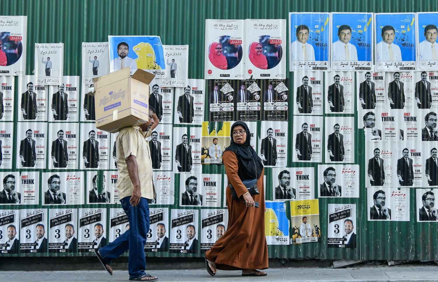 ގިނަ އަދަދަކަށް ޕޯސްޓަރު ހިއްޕާފައިހުރި ގެއެއްގެ ކައިރިން ބަޔަކު ހިނގާފައި ދަނީ---ފޮޓޯ: ނިޝާން އަލީ/މިހާރު