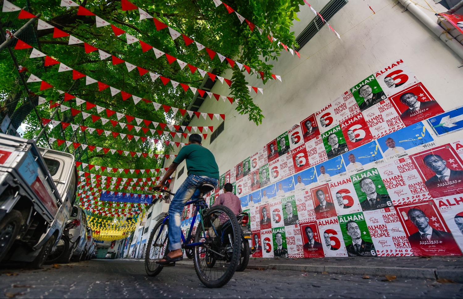 ގިނަ އަދަދެއްގެ ކެމްޕޭން ޕޯސްޓަރާއި ދިދަފަތި ހަރުކޮށްފައިހުރި މަގަކުން މީހަކު ބައިސްކަލެއްގައި ދަނީ.---ފޮޓޯ: ހުސައިން ވަހީދު/މިހާރު