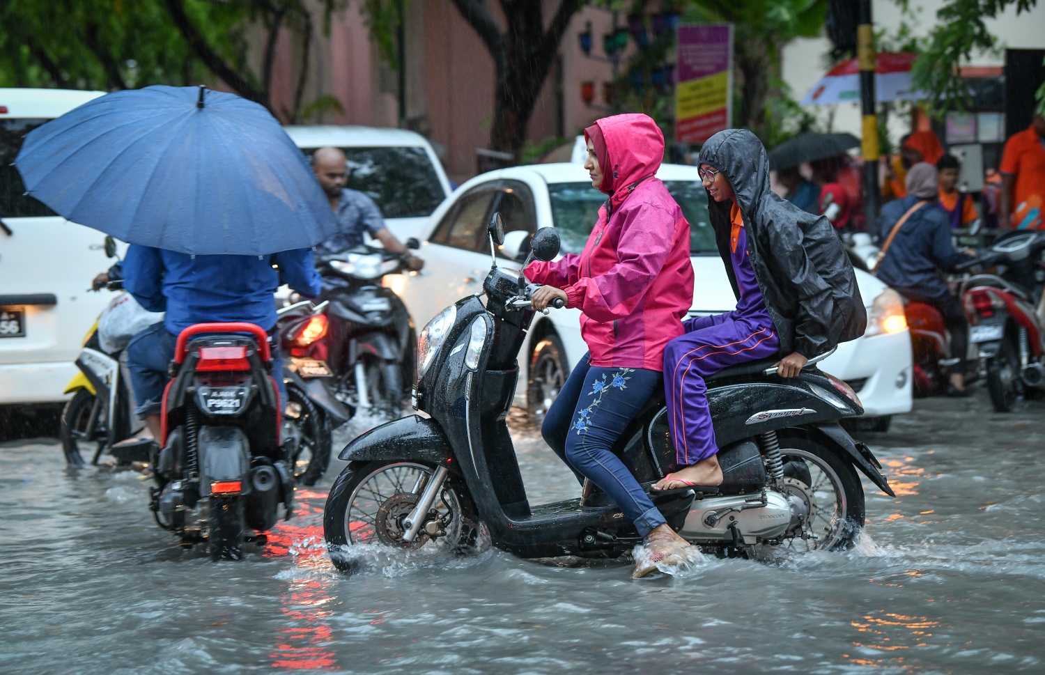 މާލެ- މެއި 23، 2019- ހުޅަނގު މޫސުމުގެ ވިއްސާރައާ އެކު މާލެ އަށް މިއަދު ހެނދުނުއްސުރެ ފެށިގެން ވެހެމުންދާ ބޯ ވާރޭގައި ފެން ބޮޑުވެފައިވާ މަގެއްގައި، މީހަކު ސްކޫލު ކުއްޖަކު ގޮވައިގެން ސައިކަލުގައި ދަނީ.---ފޮޓޯ: ނިޝާން އަލީ/މިހާރު