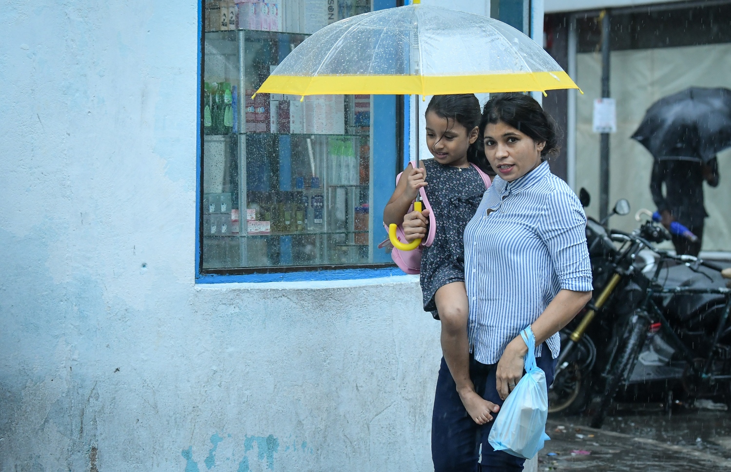 މާލެ- މެއި 23، 2019- ހުޅަނގު މޫސުމުގެ ވިއްސާރައާ އެކު މާލެ އަށް މިއަދު ހެނދުނުއްސުރެ ފެށިގެން ވެހެމުންދާ ބޯ ވާރޭގެ ތެރޭގައި ކުޑަކުއްޖަކު ގޮވައިގެން މީހަކު ކުޑަ އަޅައިގެން ހިނގާފައި ދަނީ.---ފޮޓޯ: ނިޝާން އަލީ/މިހާރު