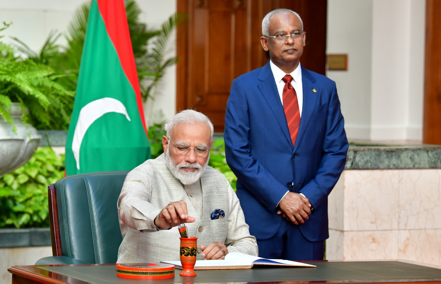 މާލެ: ޖޫން 8، 2019- އިންޑިއާގެ ބޮޑުވަޒީރު ނަރެންދުރަ މޯދީ ރަސްމީ ދަތުރުފުޅެއްގައި ރާއްޖެ ވަޑައިގަތުމަށްފަހު ރައީސް އޮފީހަށް ވަޑައިގެން މެހެމާނުންގެ ފޮތުގައި ސޮއި ކުރައްވާއިރު އަރިހުގައި ރައީސް އިބްރާހިމް މުހައްމަދު ސޯލިހް.---ފޮޓޯ: ނިޝާން އަލީ/މިހާރު