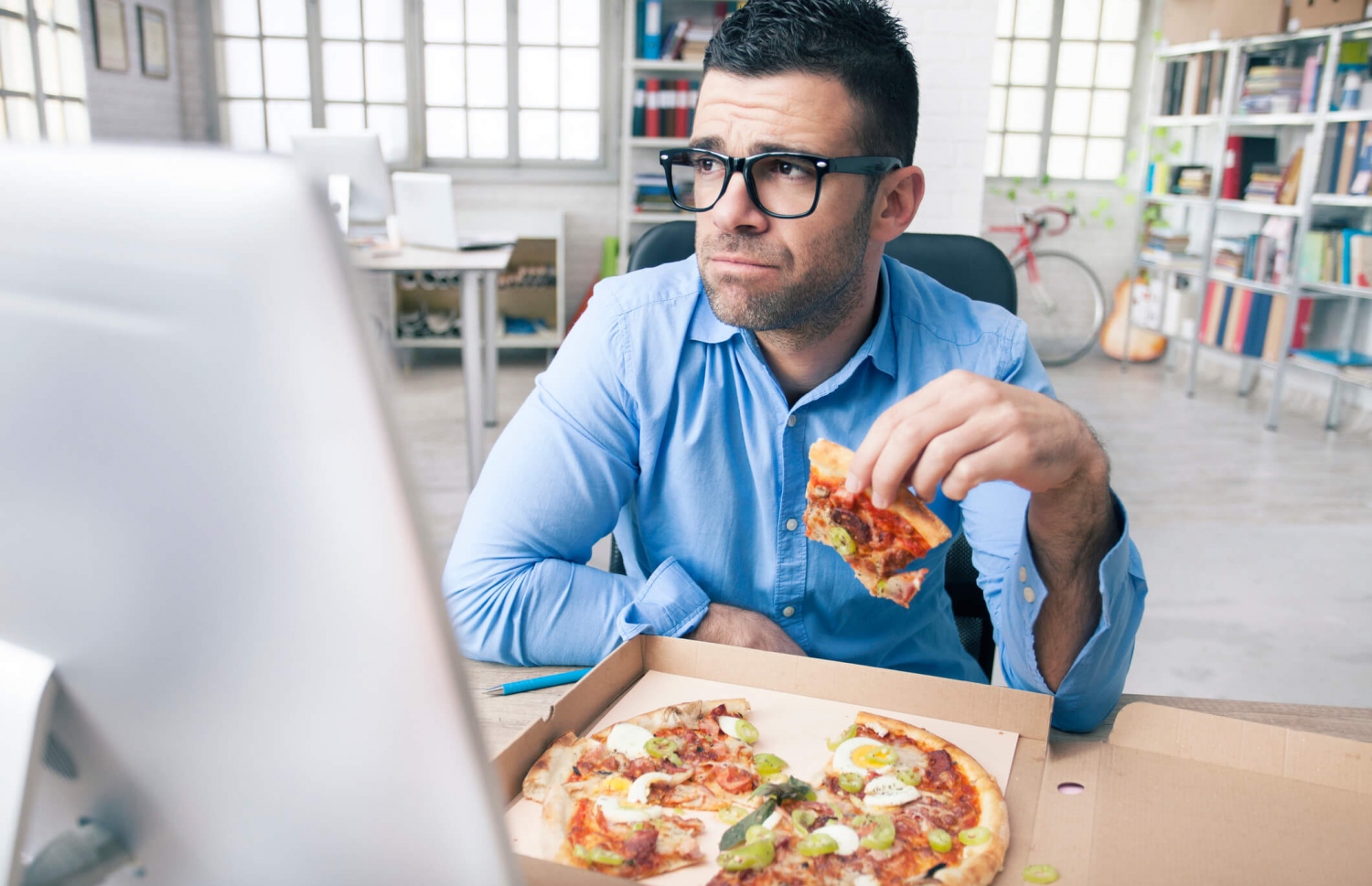 އޮފީހެއްގައި މަސައްކަތް ކުރަމުން މީހަކު ޕިއްޒާ ކަނީ.