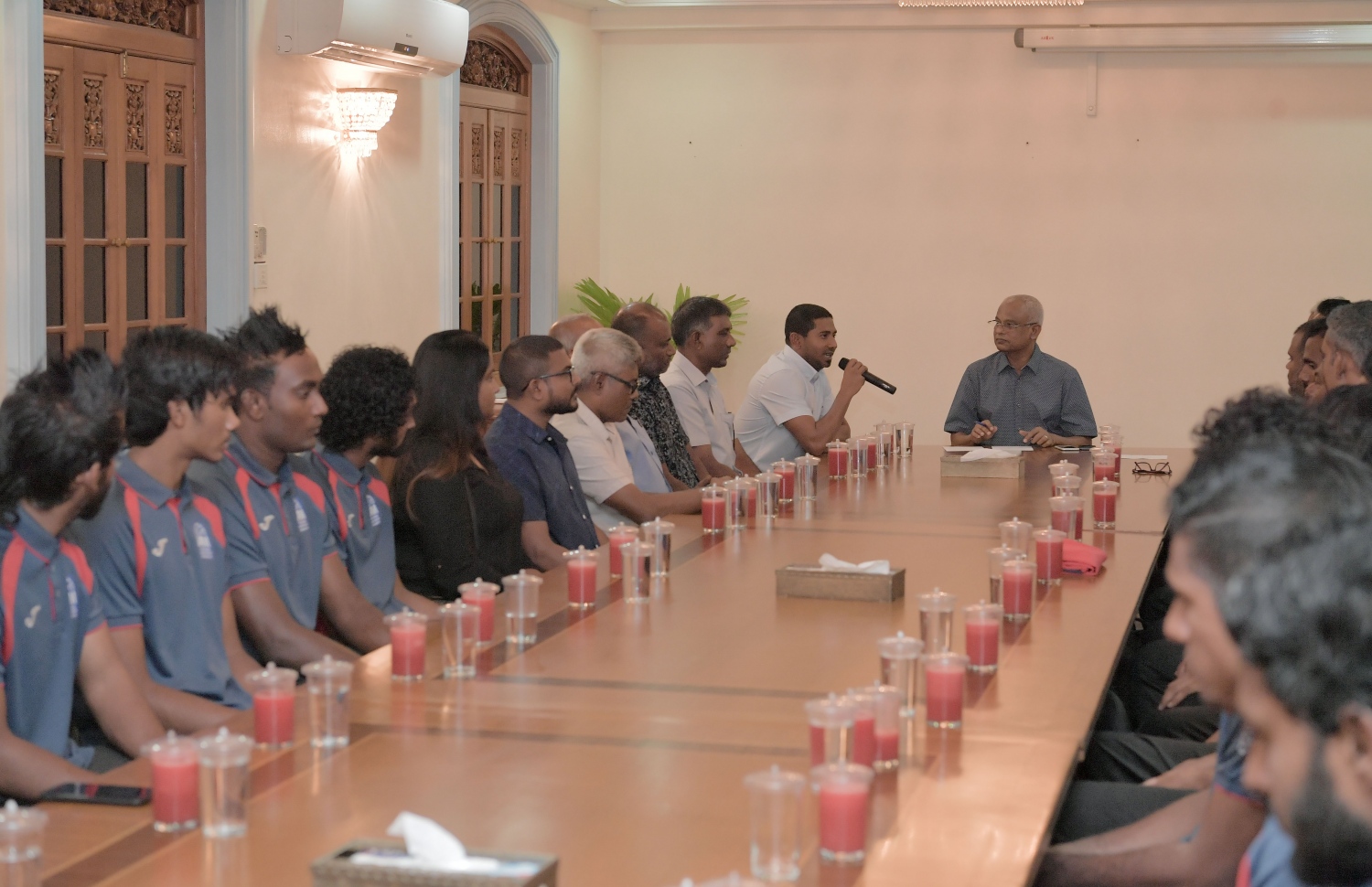 މާލެ: ޖުލައި 3، 2019: ކުރިޔަށް އޮތް އިންޑިއަން އޯޝަންސް އައިލެންޑް ގޭމްސް (އައި.އޯ.އައި.ޖީ) އަށް ތައްޔާރުވުމުގެ ގޮތުން، އިތުރު ތަމްރީނު ހޯދުމަށް ސާބިއާއަށް ދަތުރުކުރުމަށް ހަމަޖެހިފައިވާ ގައުމީ ވޮލީ ޓީމުގެ މެންބަރުންނާ ރައީސް އިބްރާހިމް މުހައްމަދު ސޯލިހު ބައްދަލު ކުރެއްވުމަށް މުލީއާގޭގައި ބޭއްވި ހަފުލާގައި ޔޫތު މިނިސްޓަރު އަހުމަދު މަހުލޫފު ވާހަކަ ދައްކަވަނީ.-- ފޮޓޯ: ރައީސް އޮފީސް