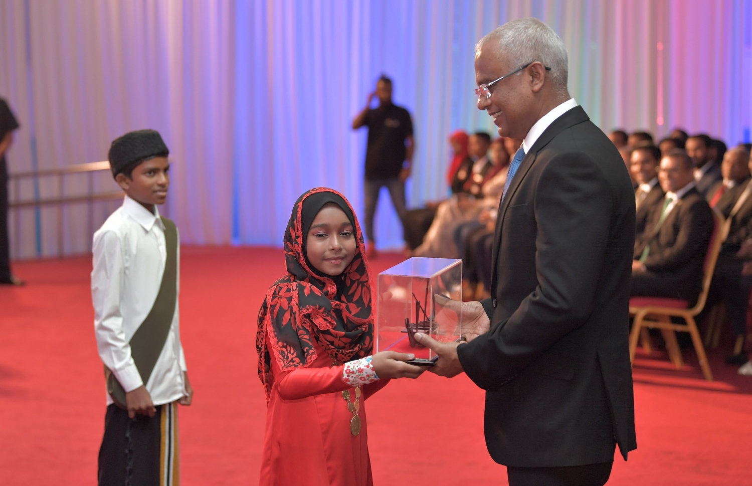 މާލެ: ޖުލައި 9، 2019: މަތީ ސާނަވީ އިމްތިހާނުގެ ގަދަ 10 ގައި ހިމެނުނު ކުދިންނަށް އިނާމު ދިނުމަށް ދަރުބާރުގޭގައި ބޭއްވި ރަސްމިއްޔާތުގައި ދަރިވަރަކު ރައީސް އިބްރާހިމް މުހައްމަދު ސޯލިހަށް ހަނދާނީ ހަދިޔާއެއް އަރުވަނީ.-- ފޮޓޯ: ރައީސް އޮފީސް