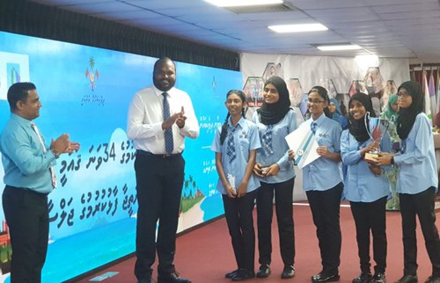 މިދިޔަ އަހަރު ބޭއްވި ވާހަކަދެއްކުމުގެ ގައުމީ މުބާރާތުން އެއް ވަނަ ހޯދި ޖަމާލުއްދީން ސްކޫލުގެ ދަރިވަރުން، ޓުއަރިޒަމް މިނިސްޓަރު އަލީ ވަހީދުގެ އަތްޕުޅުން ޓްރޮފީއާ ހަވާލުވަނީ --ފޮޓޯ: ދިވެހިބަހުގެ އެކެޑަމީ