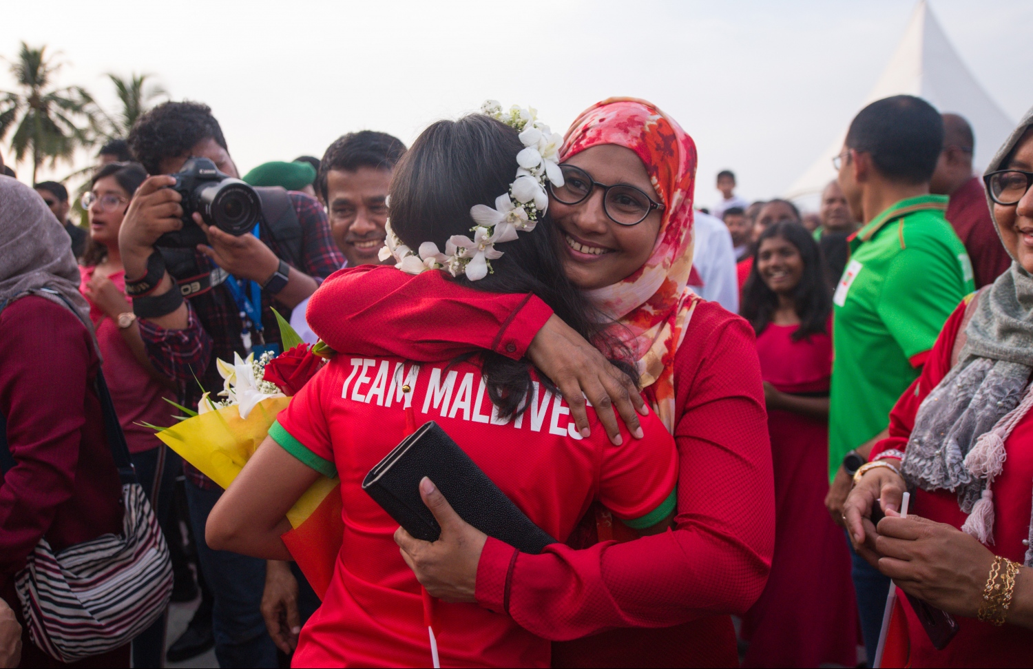 އައިއޯއައިޖީން ކާމިޔާބު ހޯދައިގެން ރަފާ އެނބުރި ރާއްޖެ އައުމުން އޭނާގެ މަންމަ ޑރ. ދީބާ (ކ) އޭނާގެ ގައިގައި ބައްދާލަނީ. --ފޮޓޯ: ހުސެއިން ވަހީދު/ މިހާރު