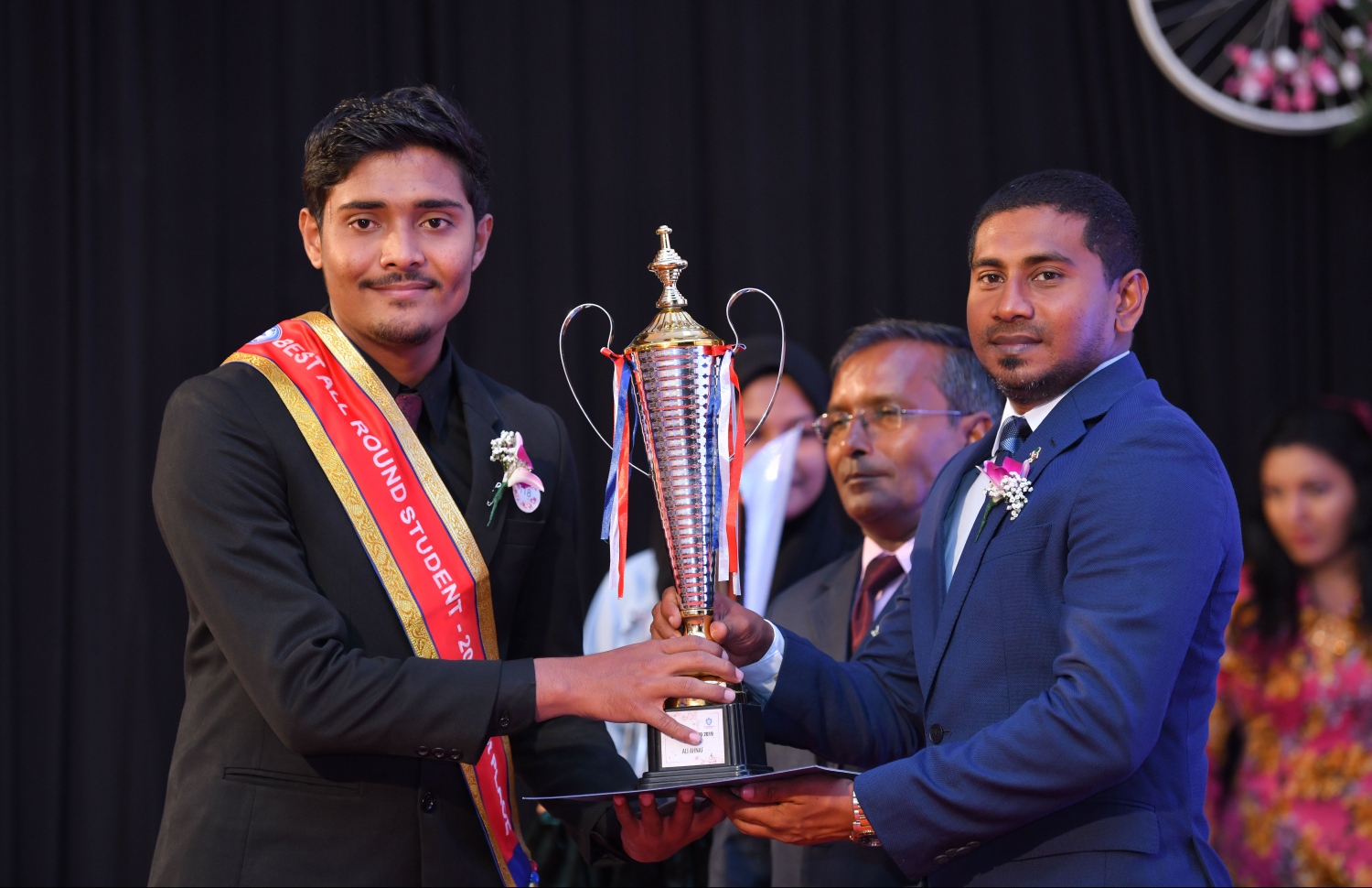 މާލެ: އޮގަސްޓް 28، 2019: ވިލާ އިންޓަނޭޝަނަލް ހައި ސްކޫލުގައި ބޭއްވި އެ ސްކޫލުގެ އިނާމުދިނުމުގެ ޖަލްސާގައި ހުރިހާ ގޮތަކުން އެންމެ މޮޅު ދަރިވަރަކަށް ހޮވުނު އަލީ އަހުނަފަށް ޔޫތު މިނިސްޓަރު އަހުމަދު މަހުލޫފު ޓްރޮފީ ހަވާލު ކޮށްދެއްވަނީ.-- ފޮޓޯ: ހުސެން ވަހީދު /މިހާރު