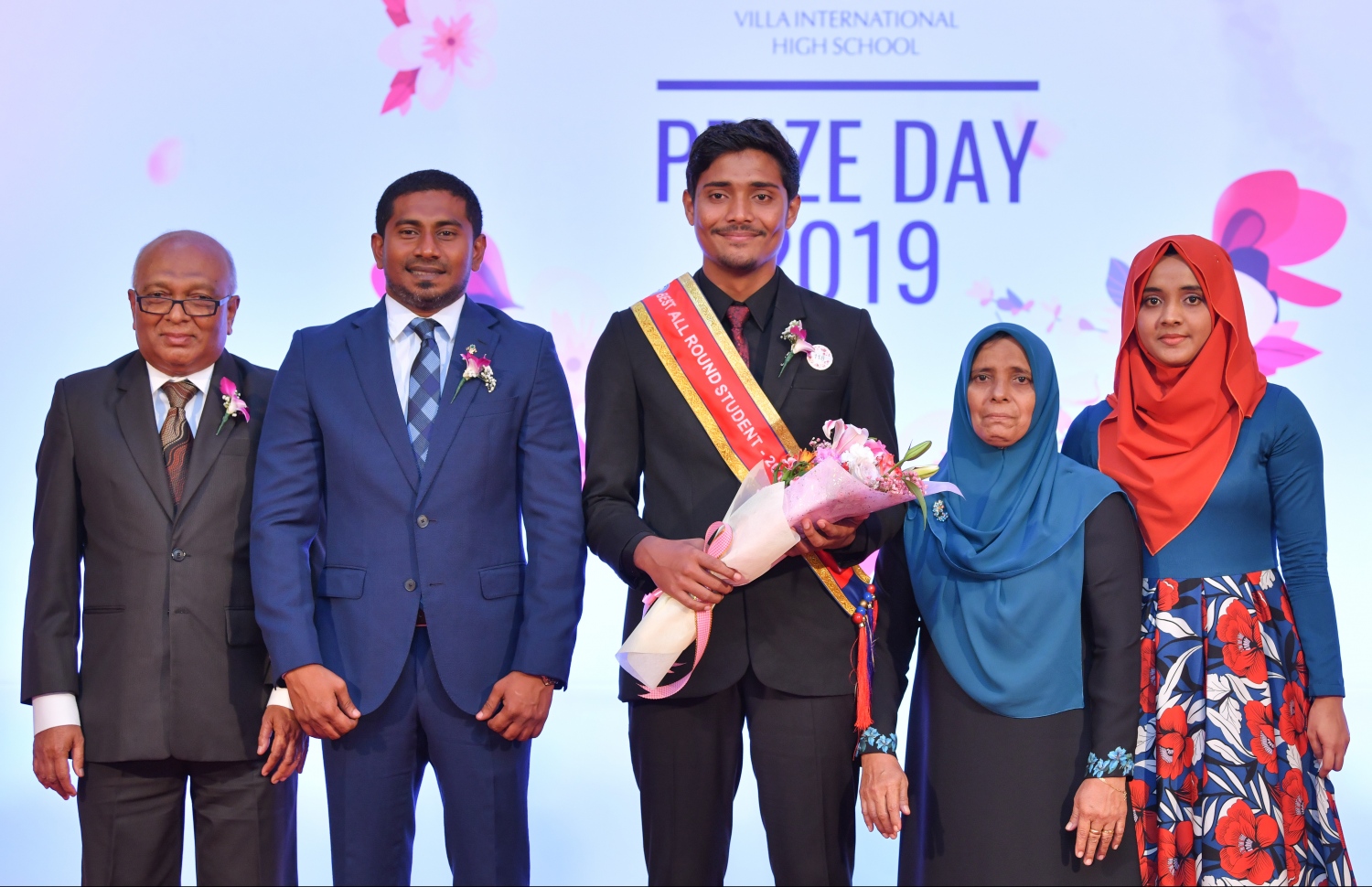 މާލެ: އޮގަސްޓް 28، 2019: ވިލާ އިންޓަނޭޝަނަލް ހައި ސްކޫލުން މިދިޔަ އަހަރު ހުރިހާ ގޮތަކުން އެންމެ މޮޅު ދަރިވަރަކަށް ހޮވި އަހުނަފު (މ) އޭނާގެ މަންމަ (ކ-2) އަދި ދައްތަ، ޔޫތު މިނިސްޓަރު މަހުލޫފު (ވ-2) އަދި ވިލާ ކޮލެޖުގެ ރެކްޓާ ޑރ. އަންވަރާއެކު ފޮޓޯއަކަށް ހުއްޓިވަޑައިގެން.- ފޮޓޯ: ހުސެއިން ވަހީދު/ މިހާރު