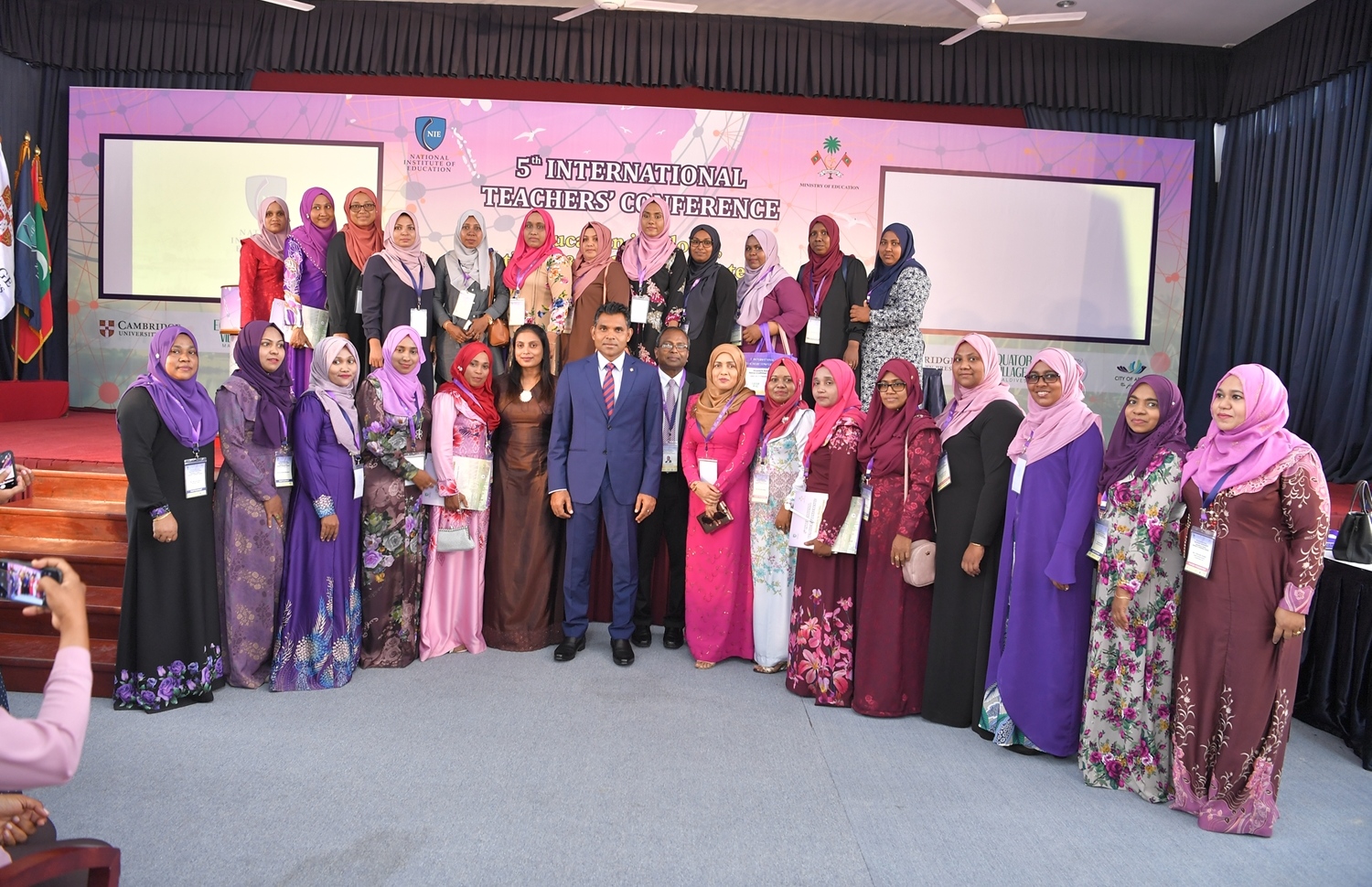 ސ. ހިތަދޫ: ސެޕްޓެމްބަރު 4، 2019: 5 ވަނަ އިންޓަނޭޝަނަލް ޓީޗާސް ކޮންފެރެންސް ފެށުމަށް ސ. ހިތަދޫ ޝަރަފުއްދީން ސްކޫލްގައި ބޭއްވި ރަސްމިއްޔާތު ނިންމަވާލުމަށްފަހު، އެ ކޮންފަރެންސްގައި ބައިވެރިވާ ބައެއް ޓީޗަރުންނާއިއެކު، ނައިބު ރައީސް ފައިސަލް ނަސީމް އަދި އެޑިއުކޭޝަން މިނިސްޓަރު އައިޝަތު އަލީ ފޮޓޯއަކަށް ހުއްޓިވަޑައިގެން.-- ފޮޓޯ: ރައީސް އޮފީސް