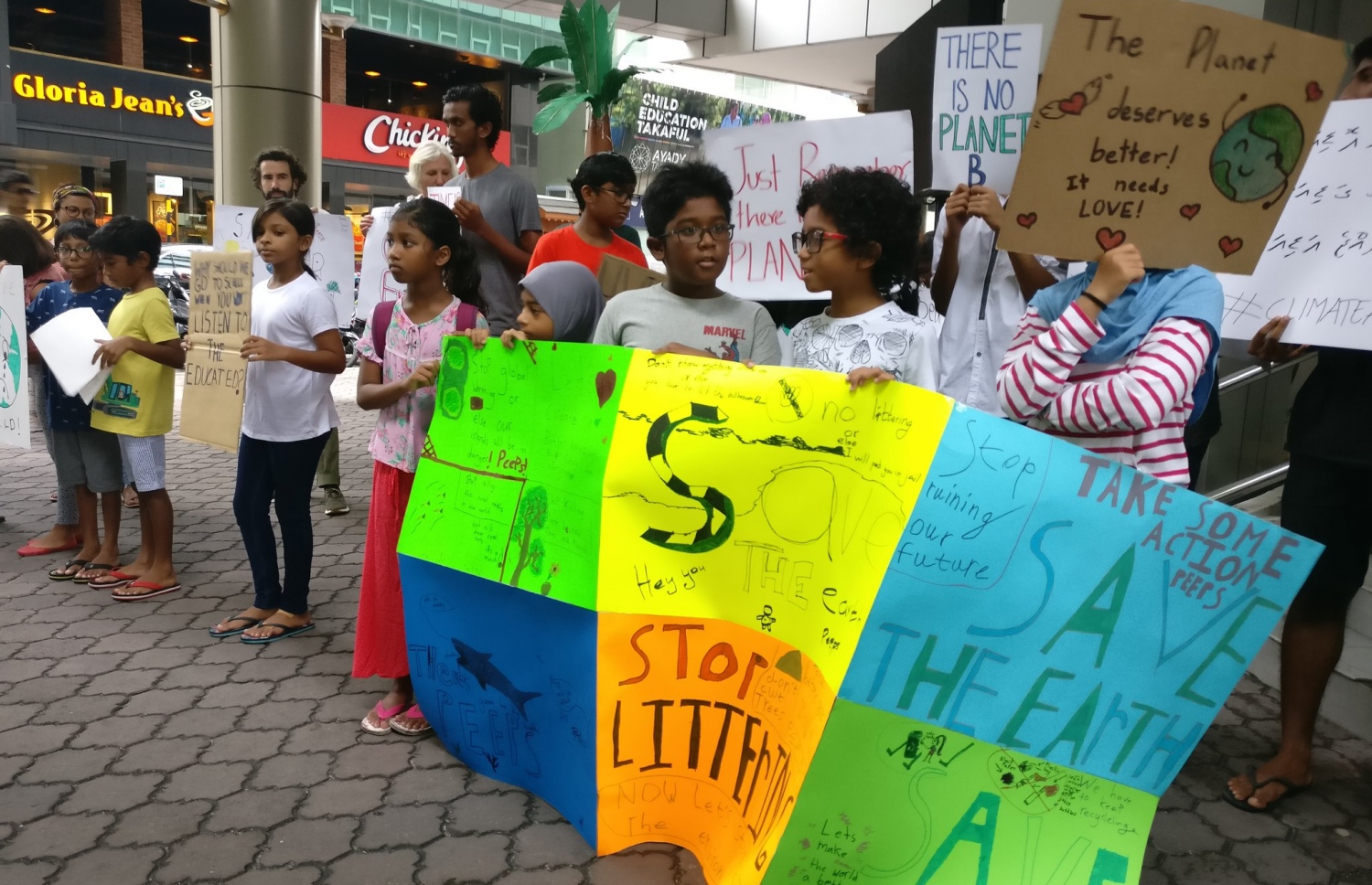 މާލެ: ސެޕްޓެމްބަރު 26، 2019: ތިމާވެއްޓަށް ދޭ ގެއްލުންތަކުން ދުނިޔެ ސަލާމަތް ކުރުމަށް ގޮވާލައި ކުރަމުންދާ ހަޅުތާލުގައި ބައިވެރިވި ކުދިންތަކެއް ތިމާވެށި ހިމާޔަތް ކޮށްދިނުމަށް ގޮވާލާ ހަދާފައިވާ ބޯޑްތަކެއް ހިފައިގެން.-- ފޮޓޯ: ސޭވް މޯލްޑިވްސް